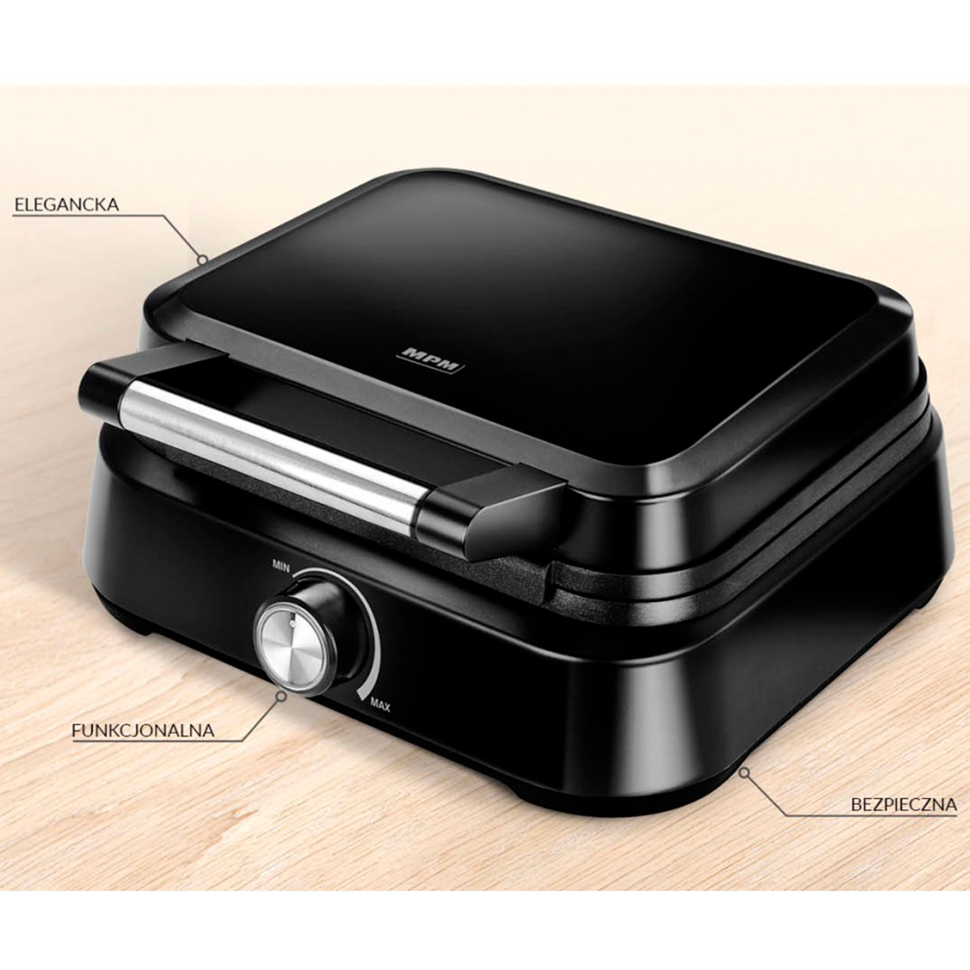 Czarny gofrownica na drewnie. Etykieta 'MPM'. Pokrętło 'MIN' i 'MAX'. Tekst 'ELEGANCJA' i 'BEZPIECZNY'.