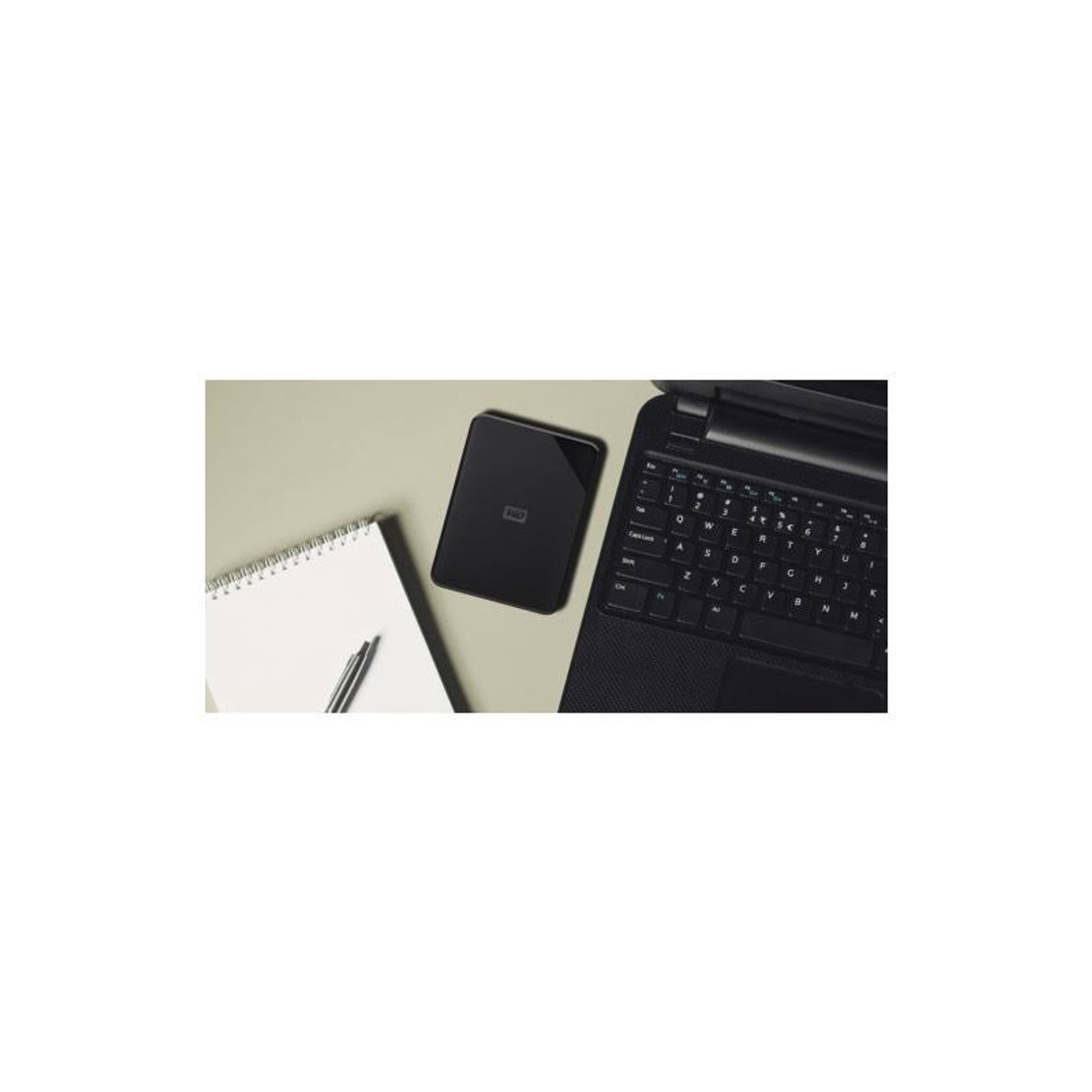 Laptop, notatnik, długopis i zewnętrzny dysk twardy na stole. Laptop jest czarny.