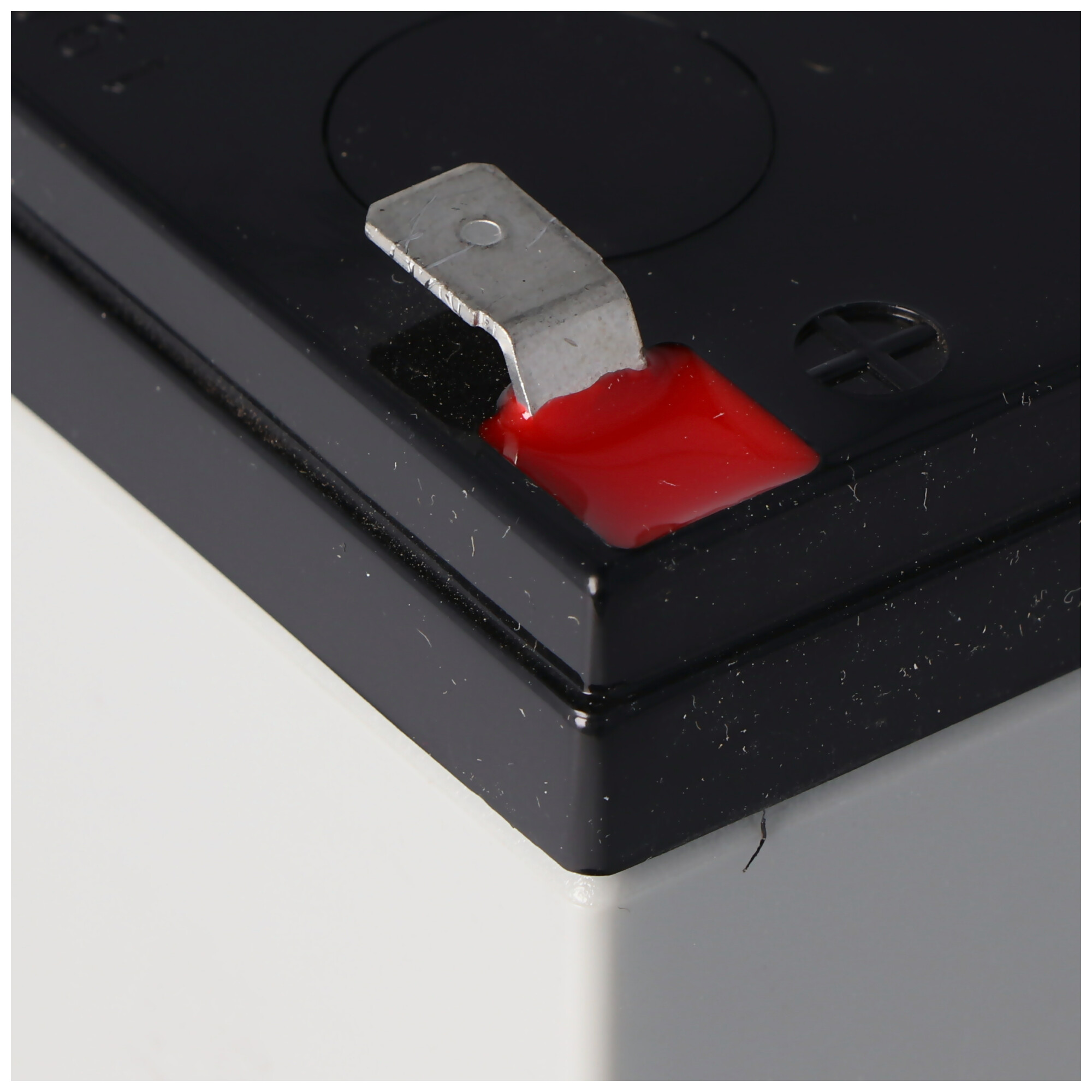 Eine schwarze Batterie mit roter Flüssigkeit in der Nähe des Pluspols.