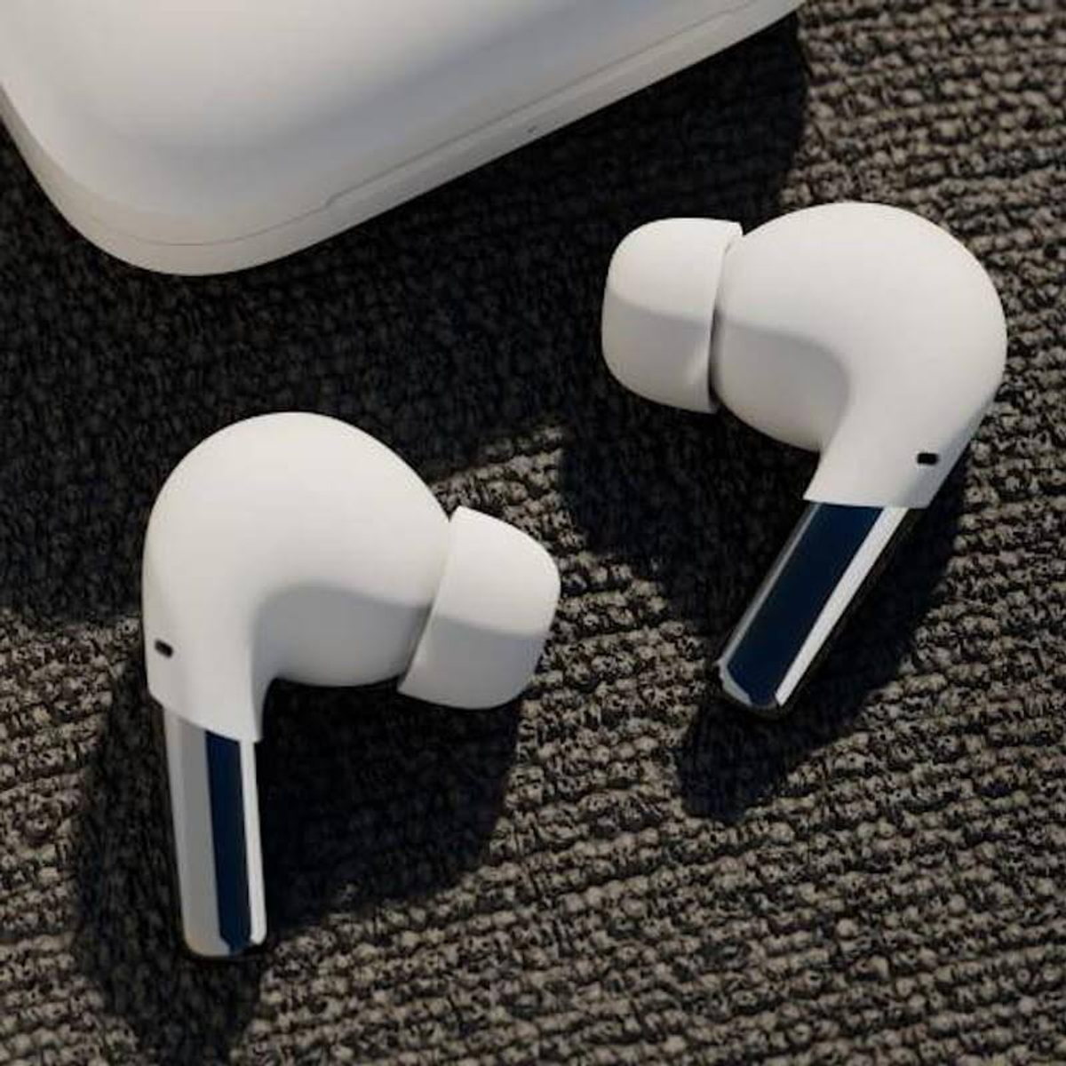 Auricolari wireless bianchi con accento blu sullo stelo, su tessuto grigio.