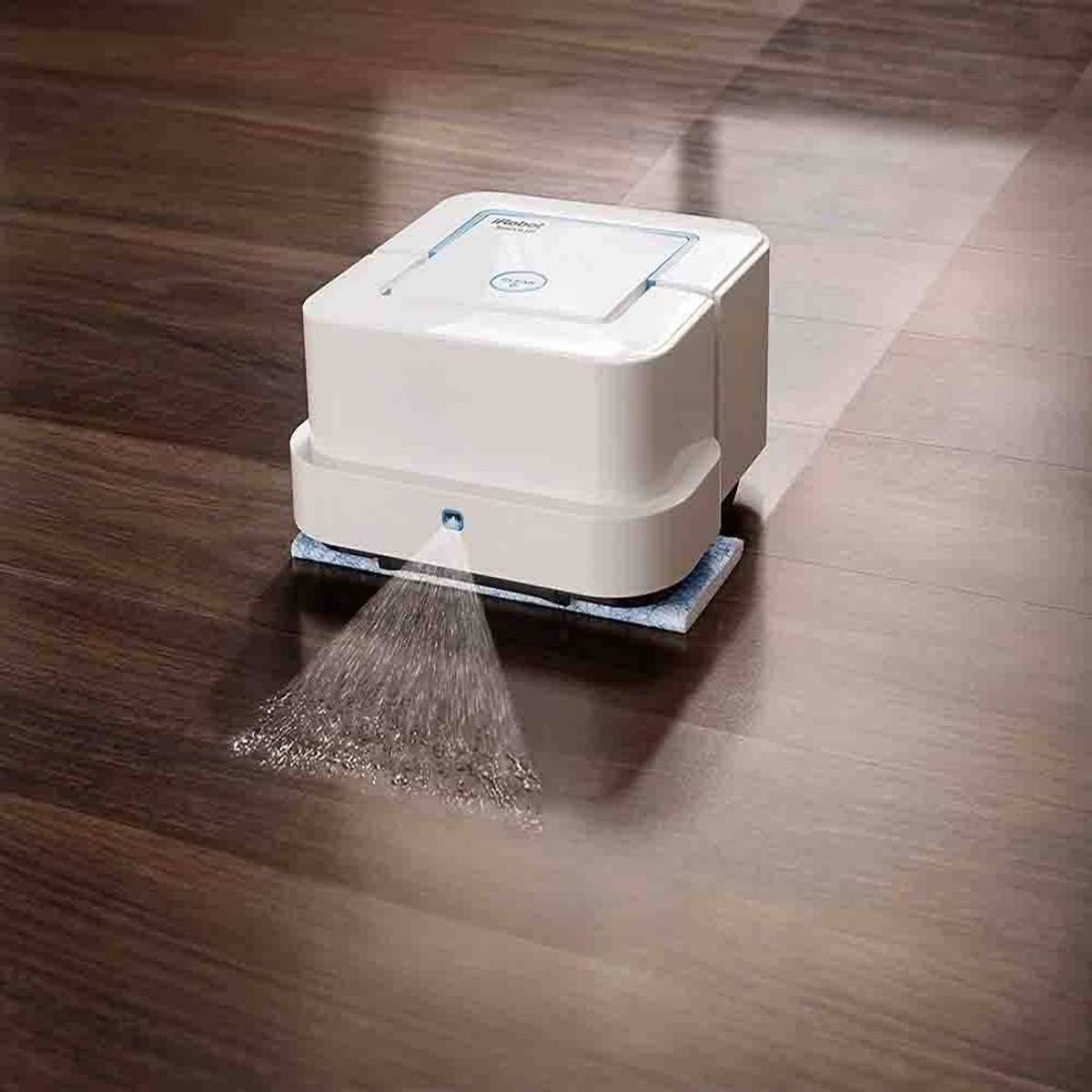 Ein weißer Roboter-Bodenreiniger, der Wasser auf einen Holzboden sprüht.