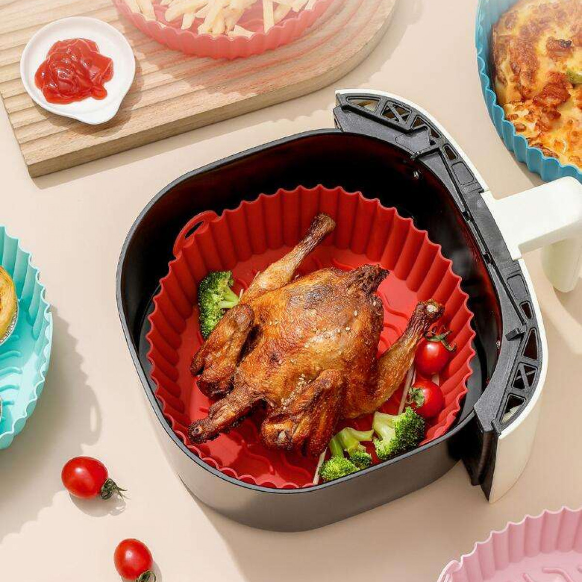 Gebratenes Huhn und Gemüse in roter Silikon-Airfryer-Form in der Heißluftfritteuse.
