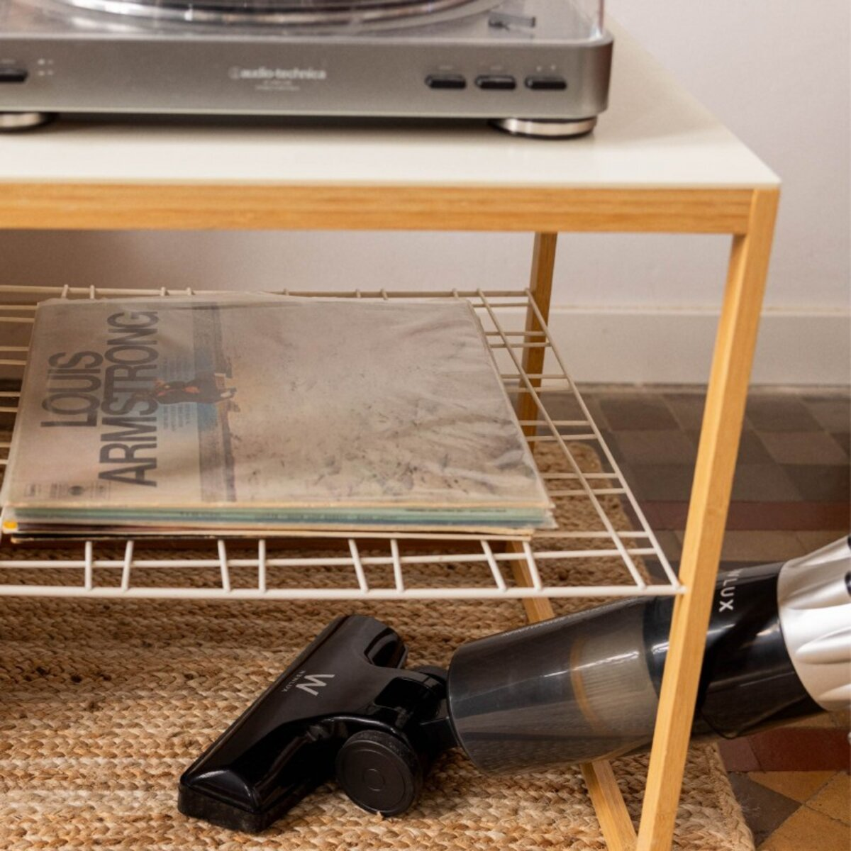 Aspiradora negra y plateada en uso cerca de una mesa con un tocadiscos y discos de vinilo.