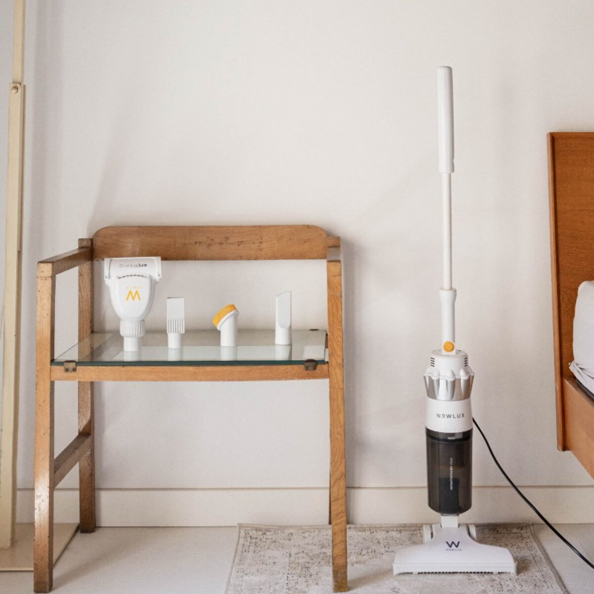Aspiradora blanca y negra, y accesorios en una estantería de madera. Fondo blanco.