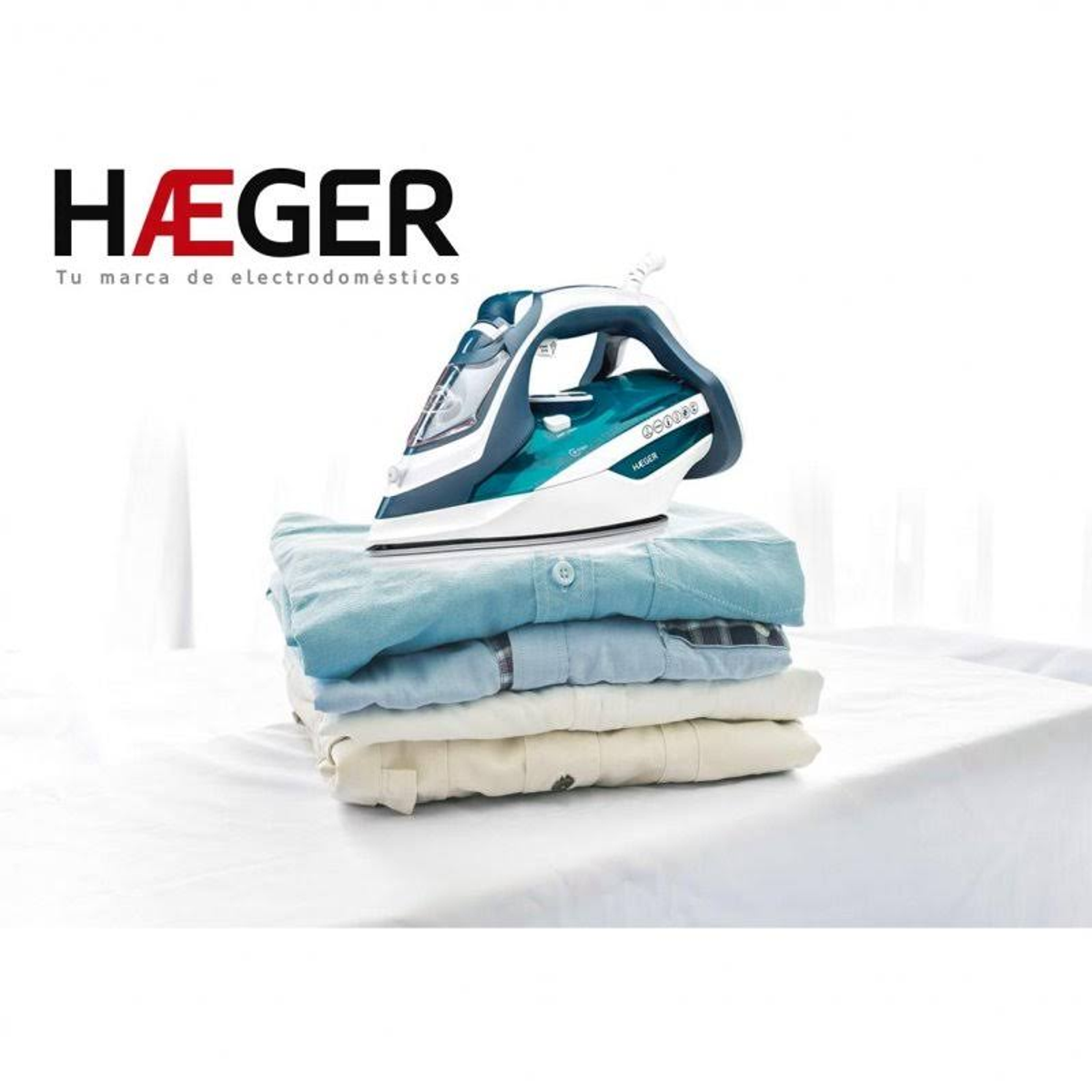 Ein Bügeleisen auf einem Stapel gefalteter Hemden auf einer weißen Oberfläche, mit HAEGER-Logo.