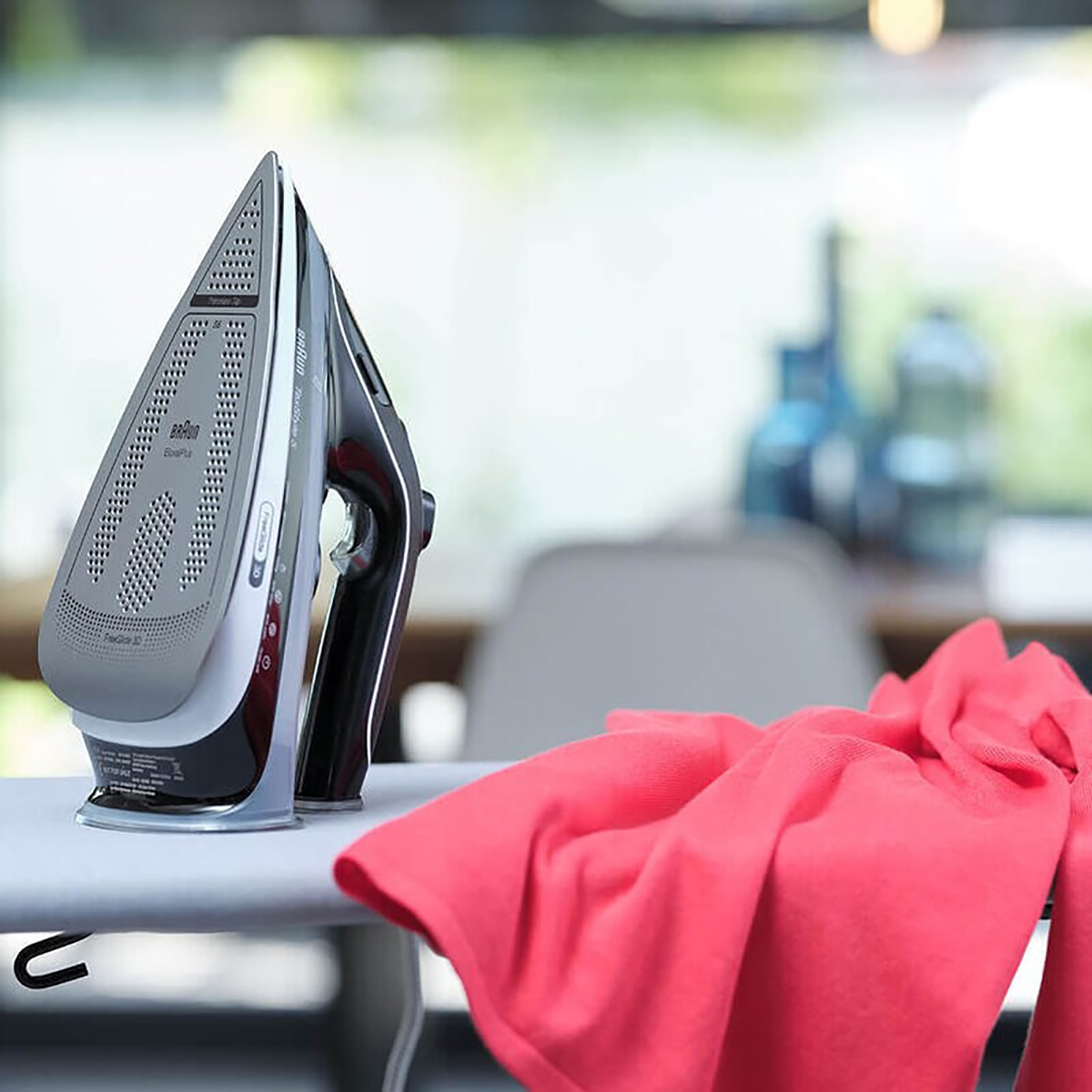 Żelazko i deska do prasowania z czerwoną szmatką.