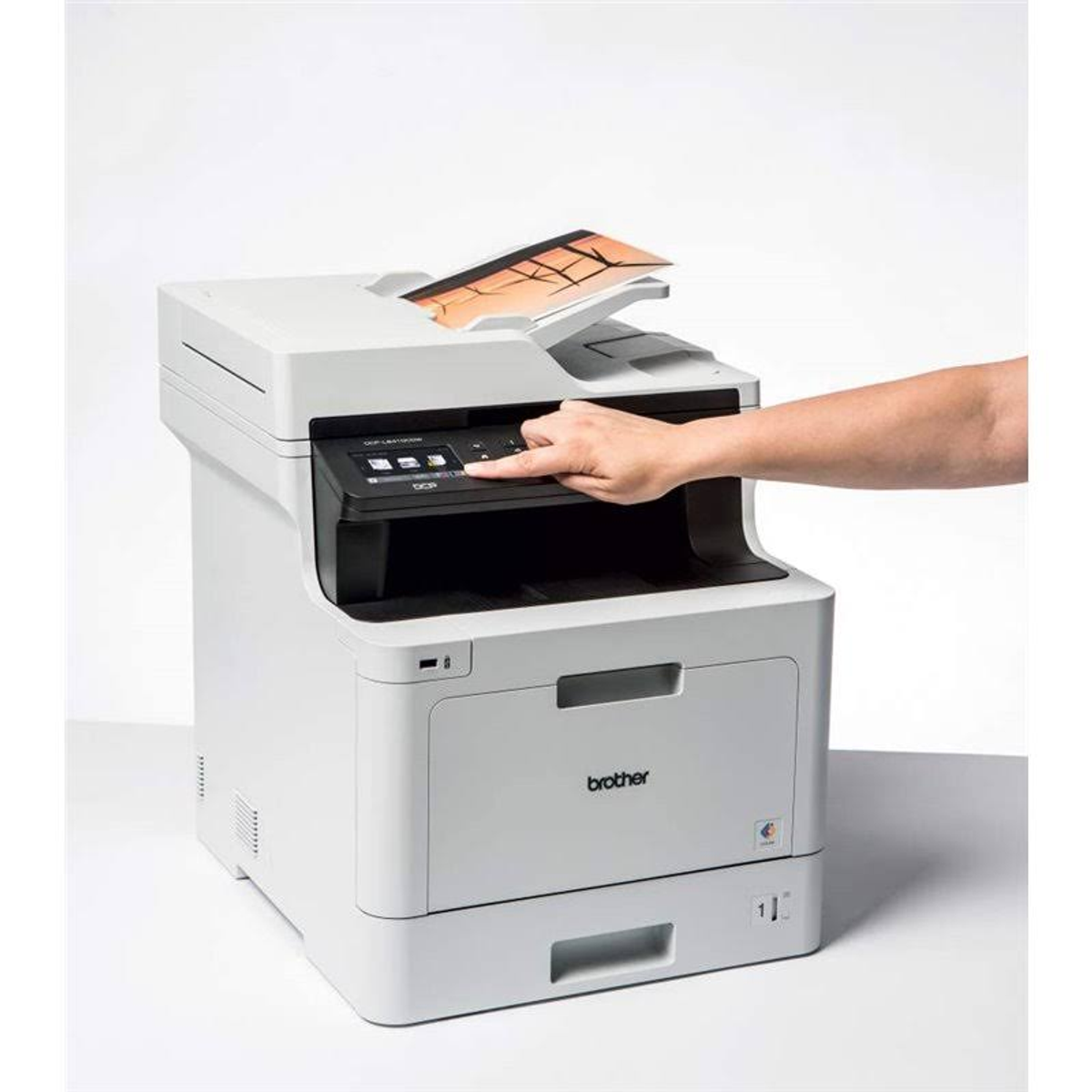 Weißer Drucker mit einer Hand, die eine Taste drückt. Brother-Logo sichtbar.