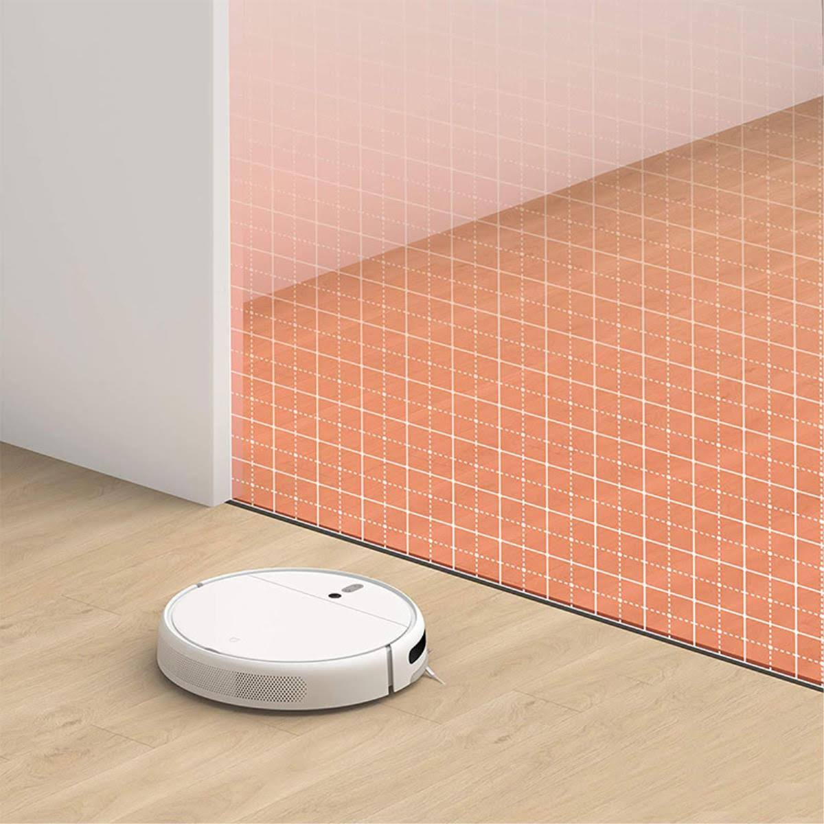 Una aspiradora robot blanca en un suelo de madera. Una cuadrícula de mapeo es visible en la alfombra naranja.