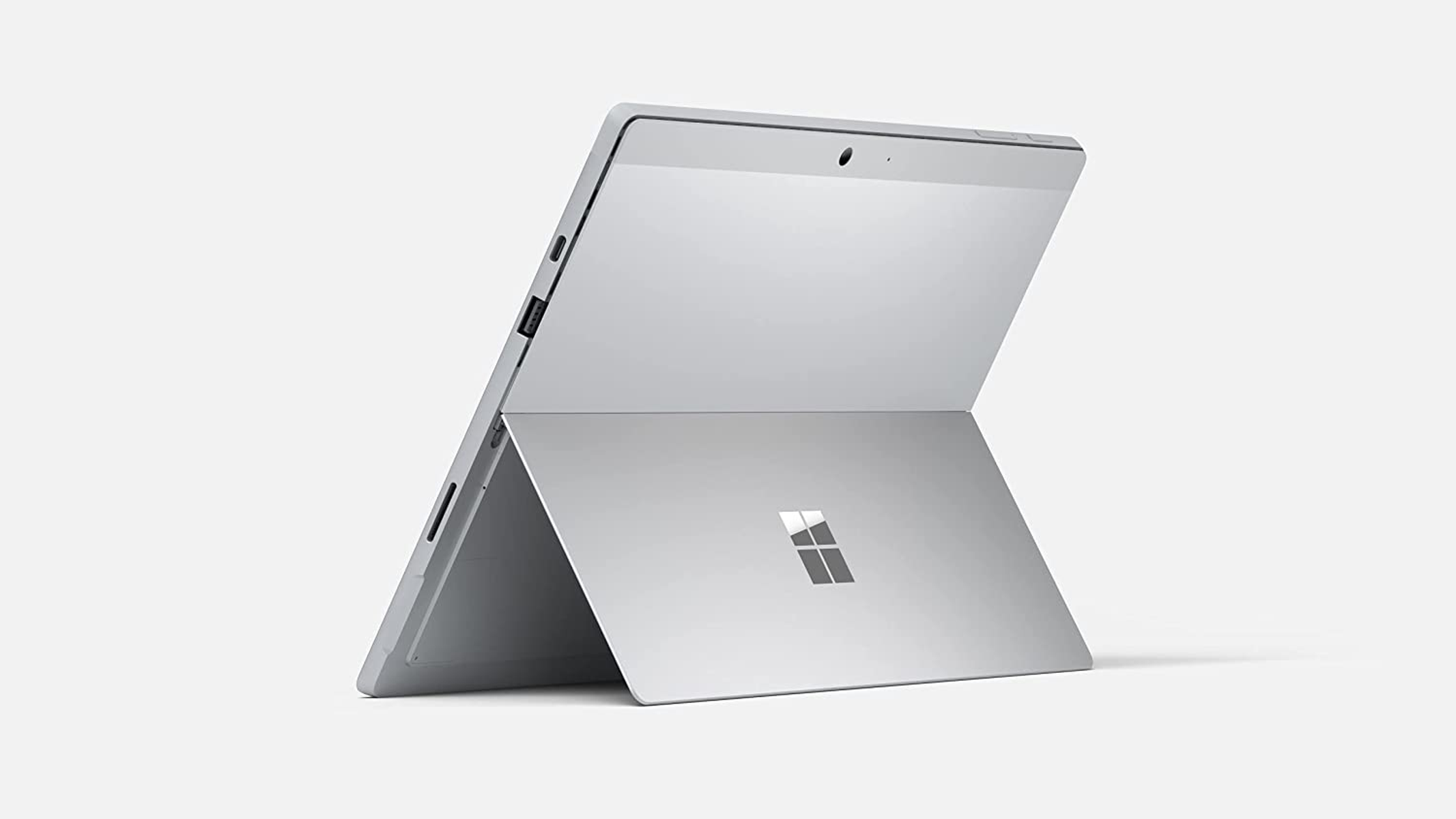 Una tableta de color claro apoyada. El logotipo de Microsoft es visible, con un fondo blanco y una cámara.