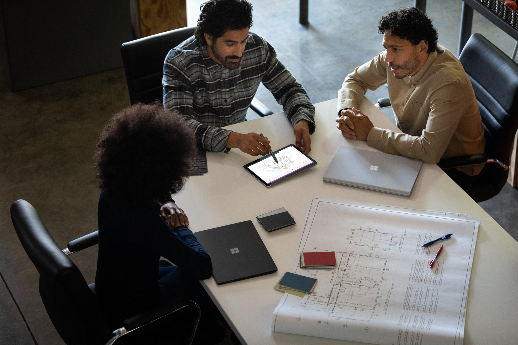 Tre persone intorno a un tavolo che lavorano con un tablet e documenti.
