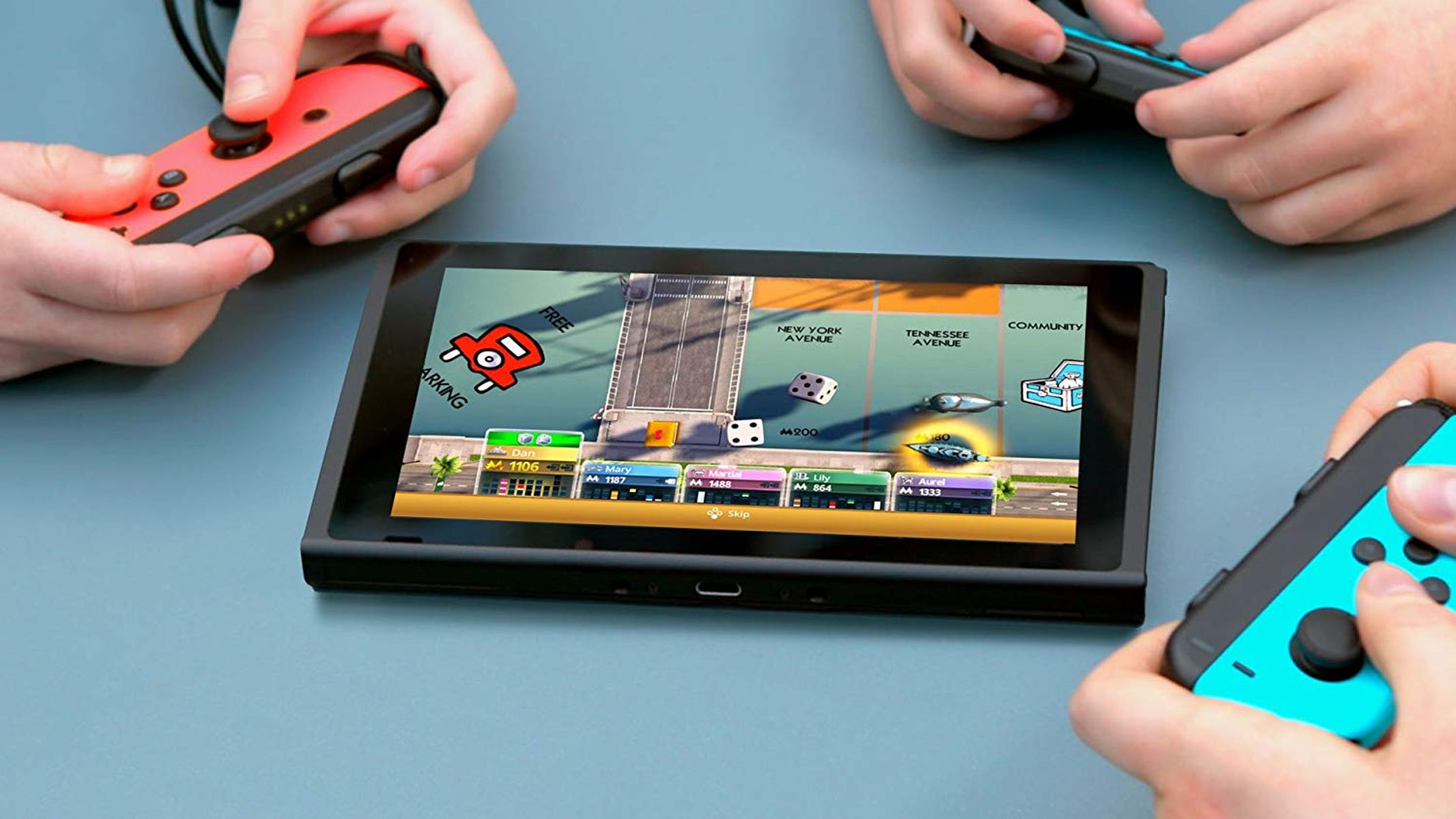 Hände halten Gamecontroller und spielen ein Spiel auf einem Tablet. Monopoly-Spielbildschirm sichtbar.