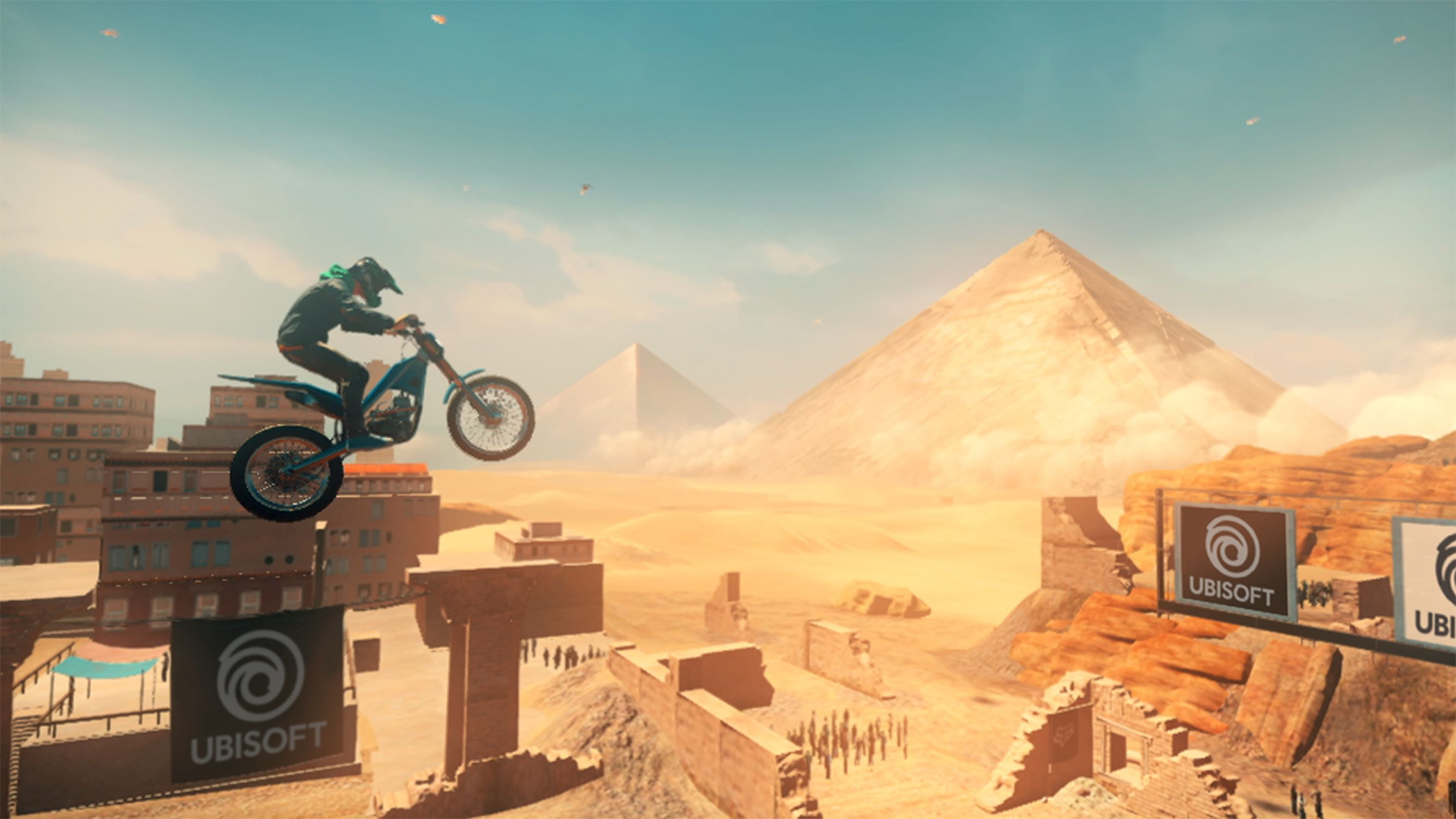 Ein Motocross-Fahrer springt über eine Rampe, mit Pyramiden und Wüste im Hintergrund.