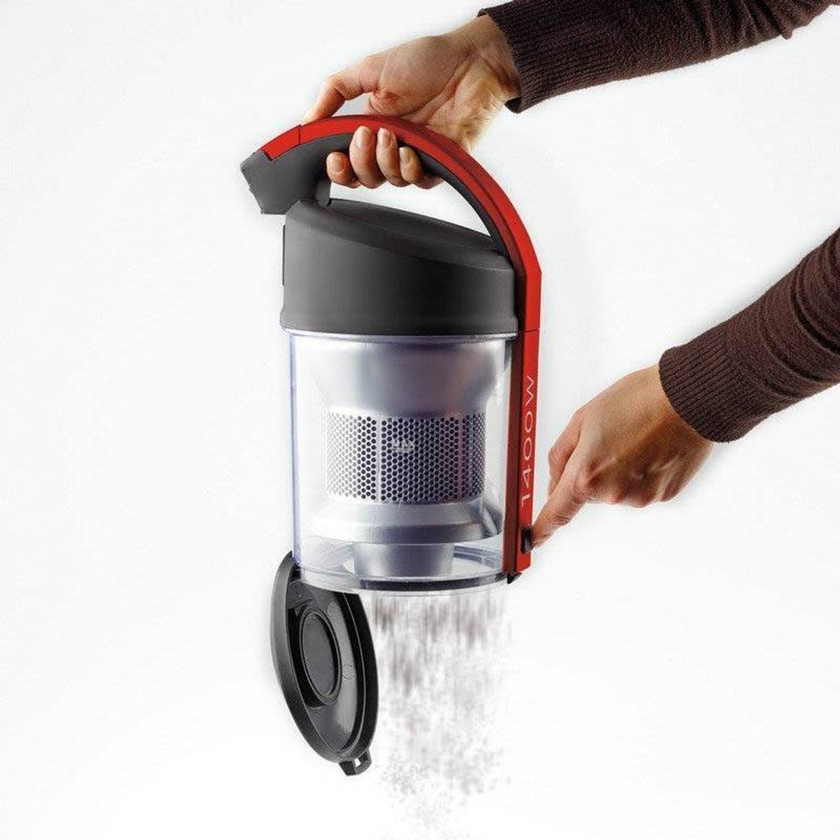 Ręce trzymają czerwony i czarny odkurzacz, z którego wychodzą białe resztki.