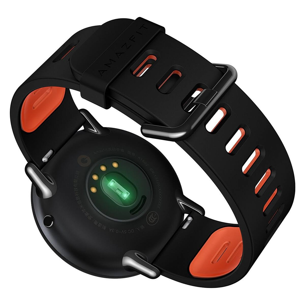 Smartwatch negra, vista trasera. Acentos naranjas en la correa. Luz verde en el sensor.
