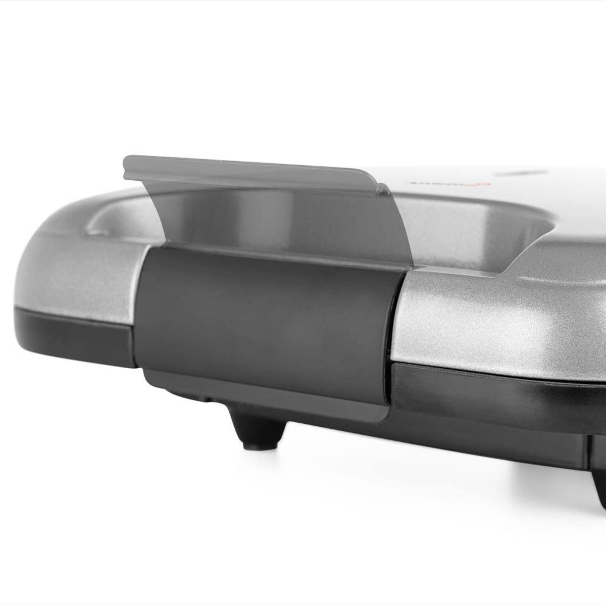 Primer plano de un electrodoméstico plateado y negro con asa, parte de un dispositivo de cocina.