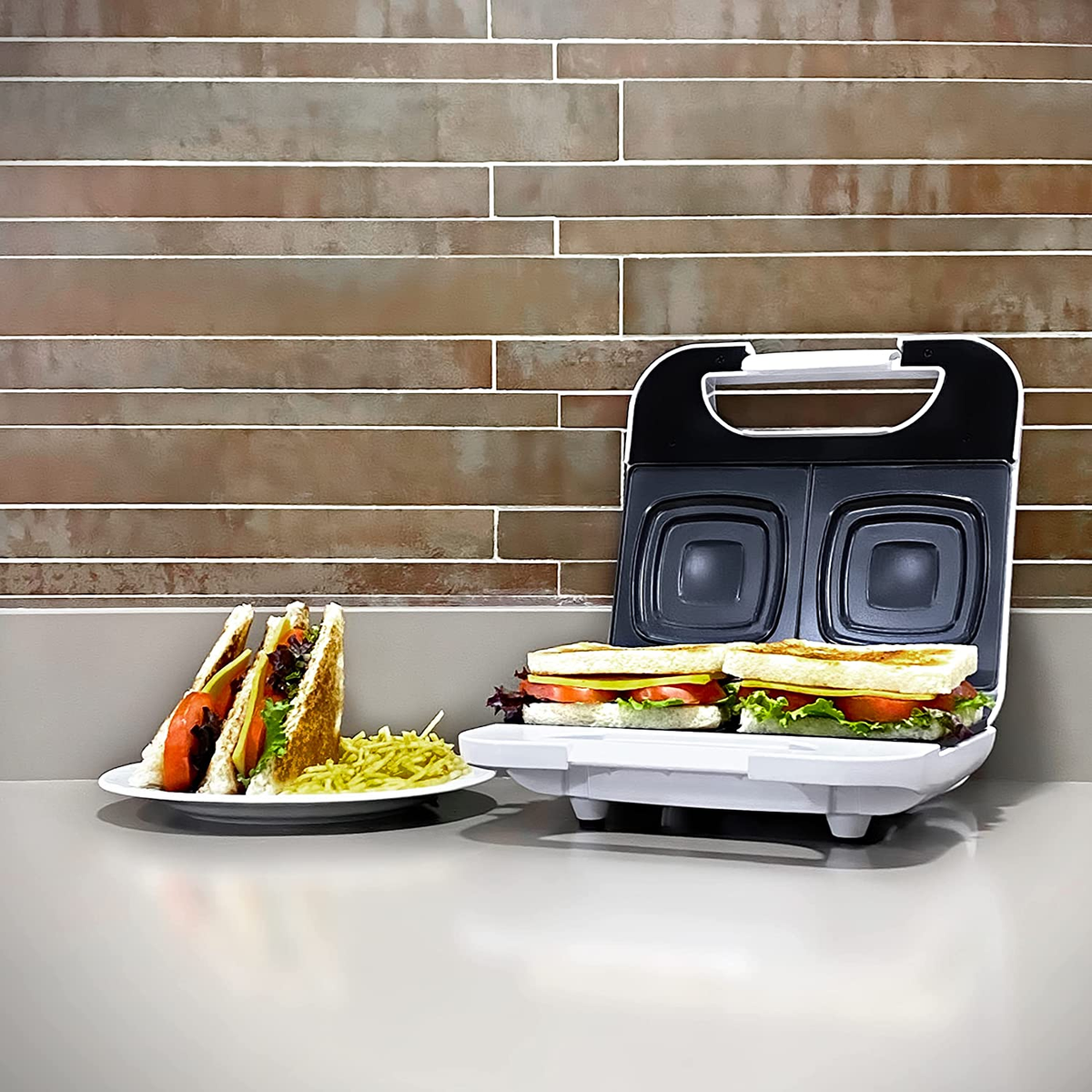 Sándwiches en un plato y en una sandwichera. Tostados, con tomate y lechuga.