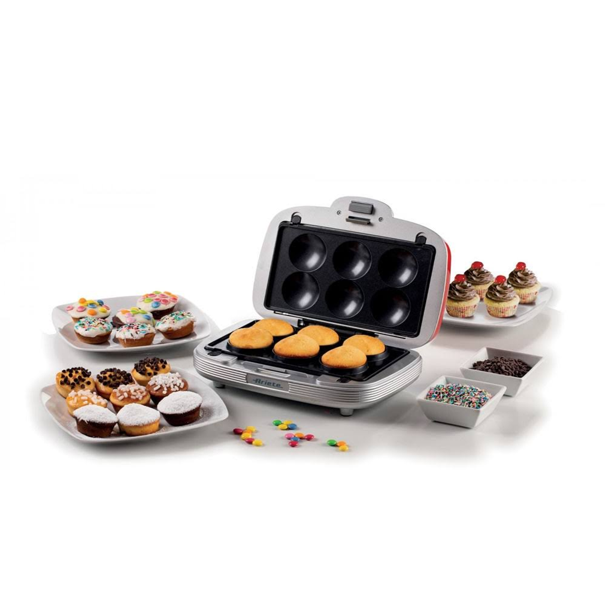 Cupcake maker with cooked cakes and toppings on plates. Silver body, red accents.