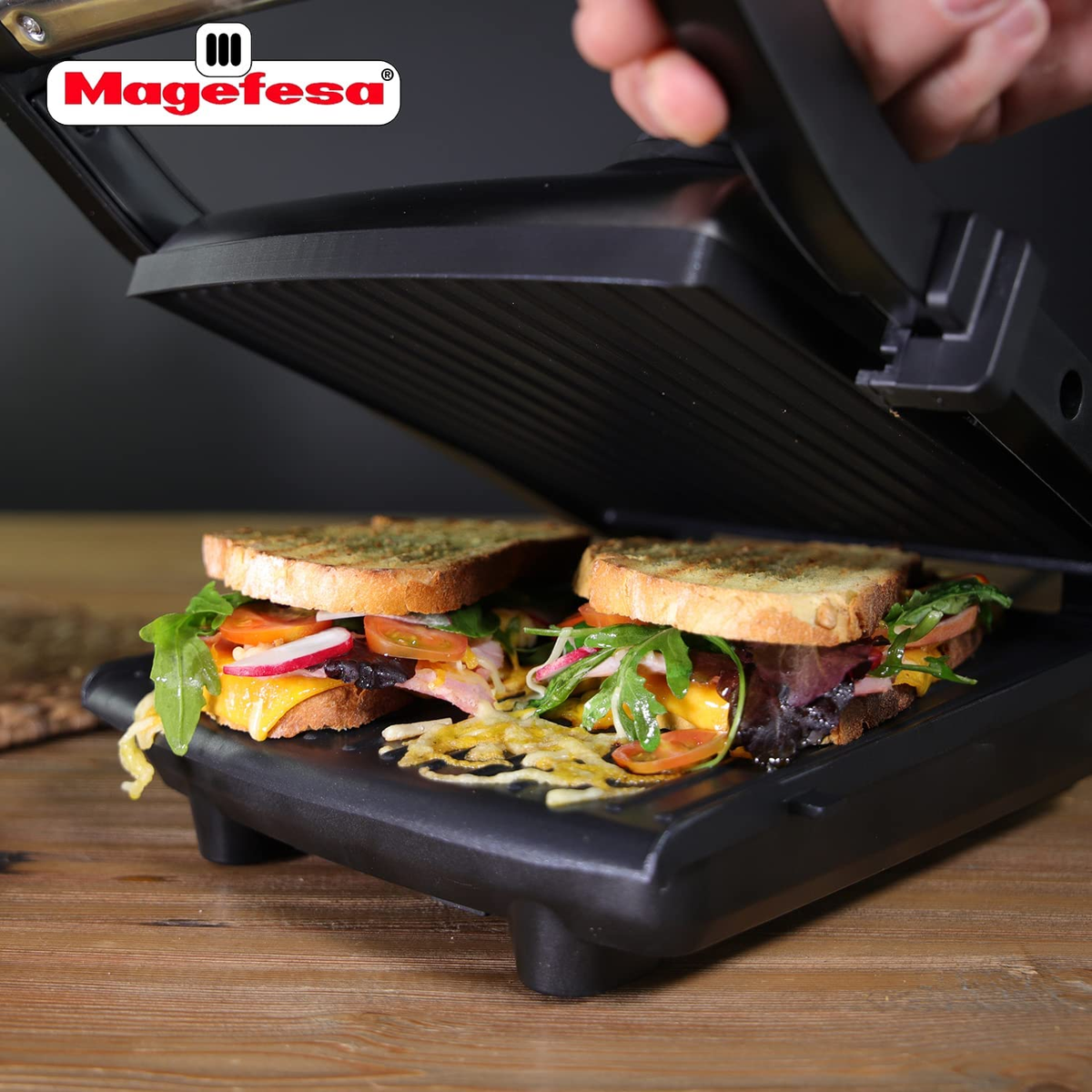Una sandwichera con dos sándwiches dentro, uno abierto. La marca Magefesa es visible.