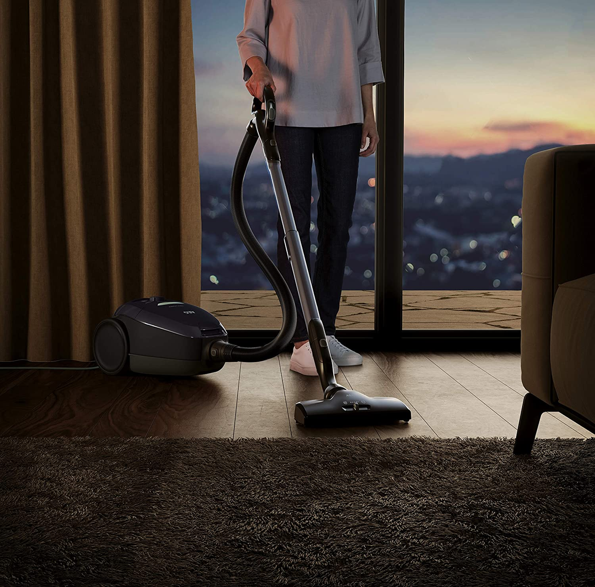 Osoba odkurzająca pokój, z widokiem na zachód słońca.