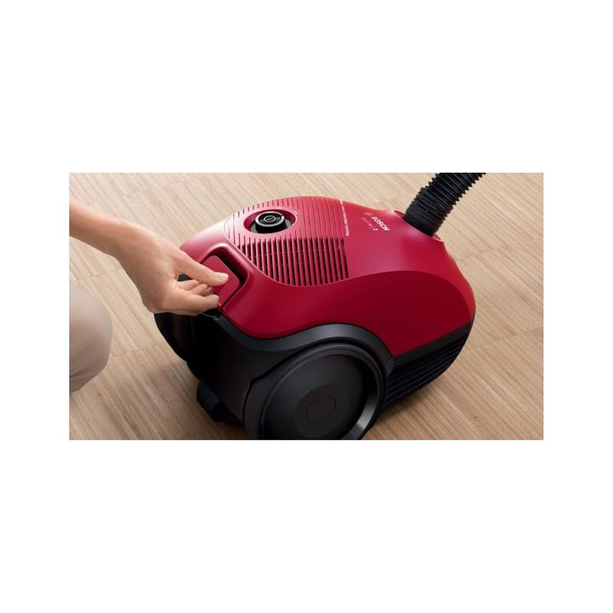 Czerwony odkurzacz z uchwytem na drewnianej podłodze.