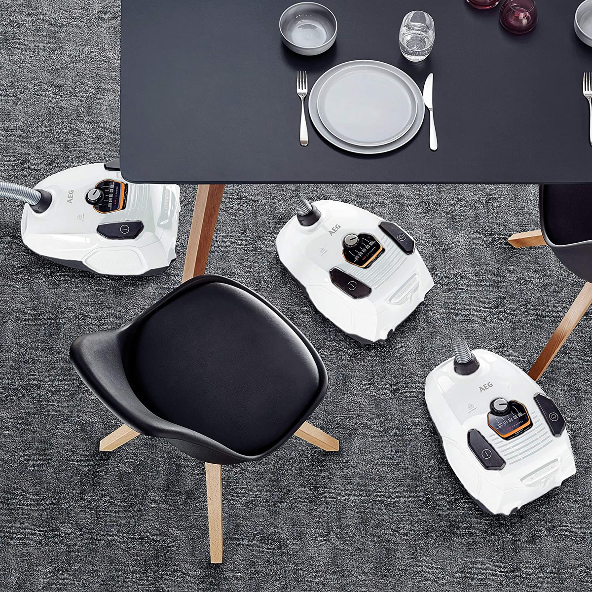 Odkurzacze i meble na szarym dywanie. Czarny stół i krzesło. Ujęcie z góry.