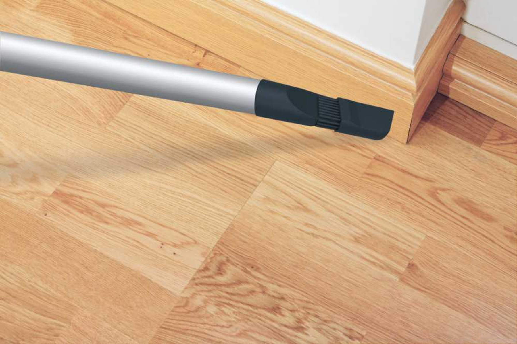 Głowica odkurzacza czyszcząca podłogę. Drewniana podłoga na pierwszym planie.