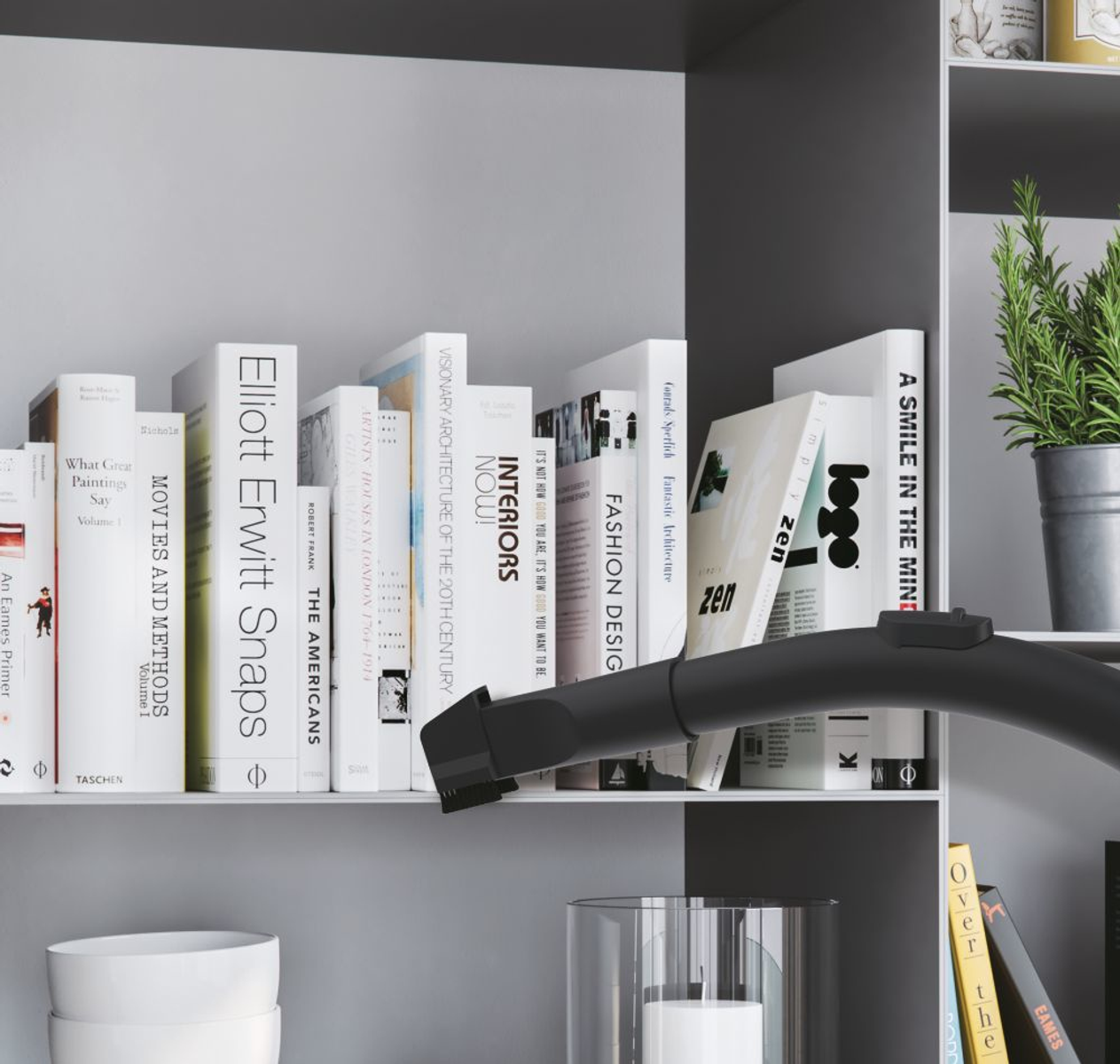 Półka z książkami. Dysza odkurzacza czyszcząca półkę.