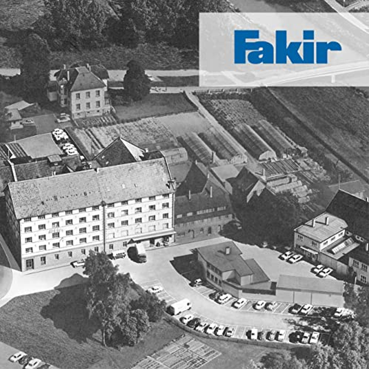 Luftaufnahme von Gebäuden, Parkplätzen und Feldern. Das Fakir-Logo befindet sich oben rechts.