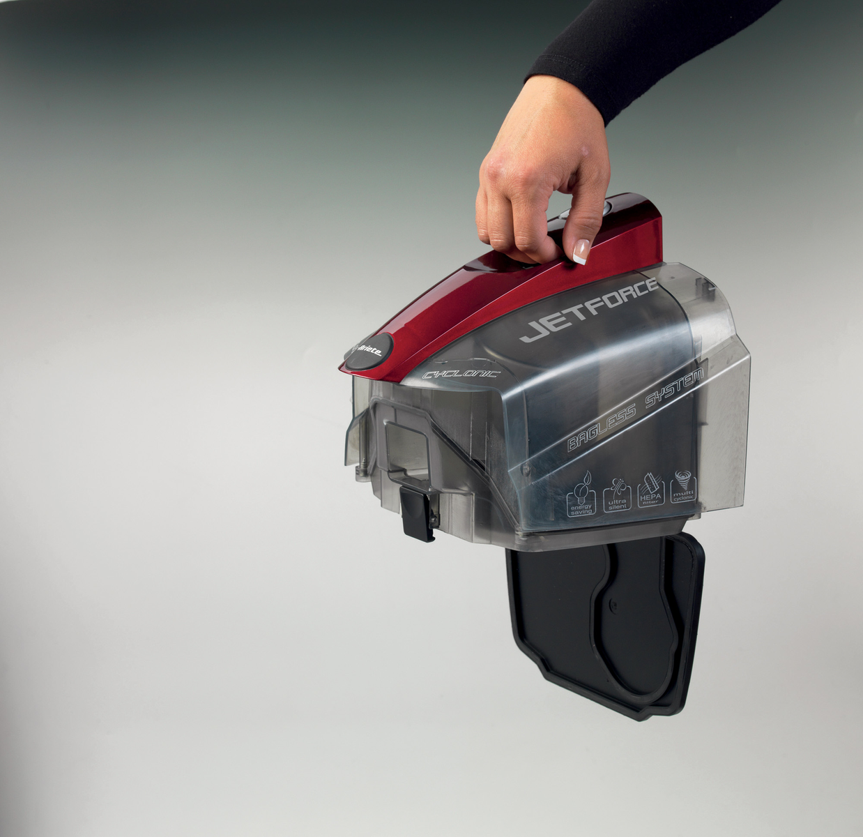 Ręka trzymająca czerwony i przezroczysty pojemnik. Pojemnik ma czarną pokrywę.