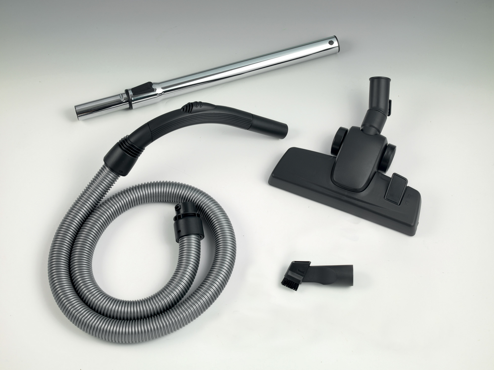 Części odkurzacza: wąż, rura i głowica na białym tle. Czarne i srebrne elementy.