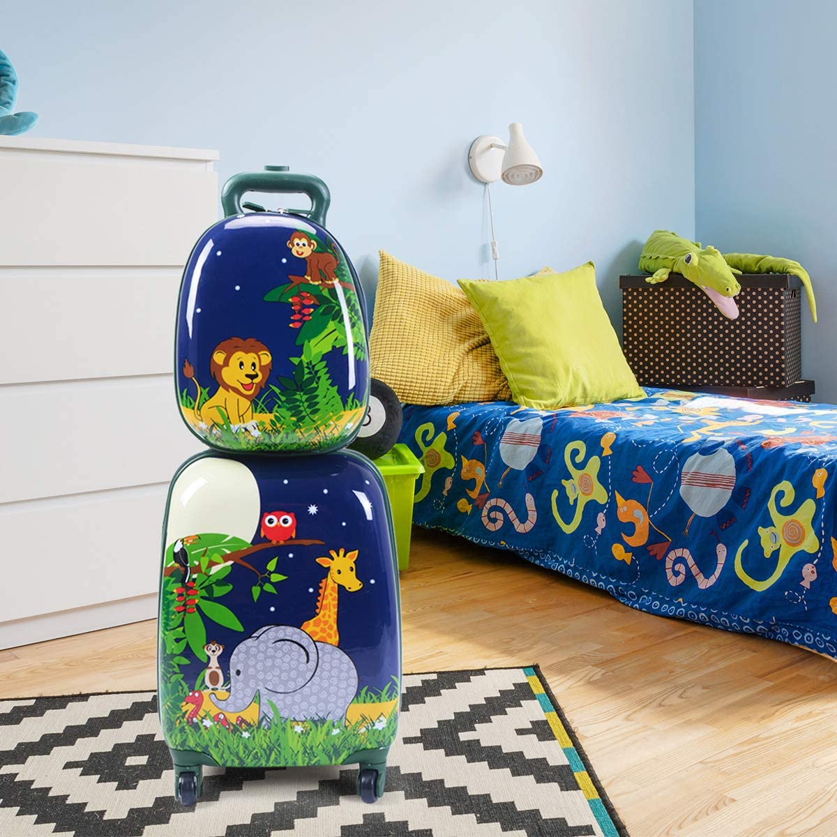 Zwei cartoonartig dekorierte Koffer, gestapelt in einem Kinderzimmer. Bett und Kommode im Hintergrund.