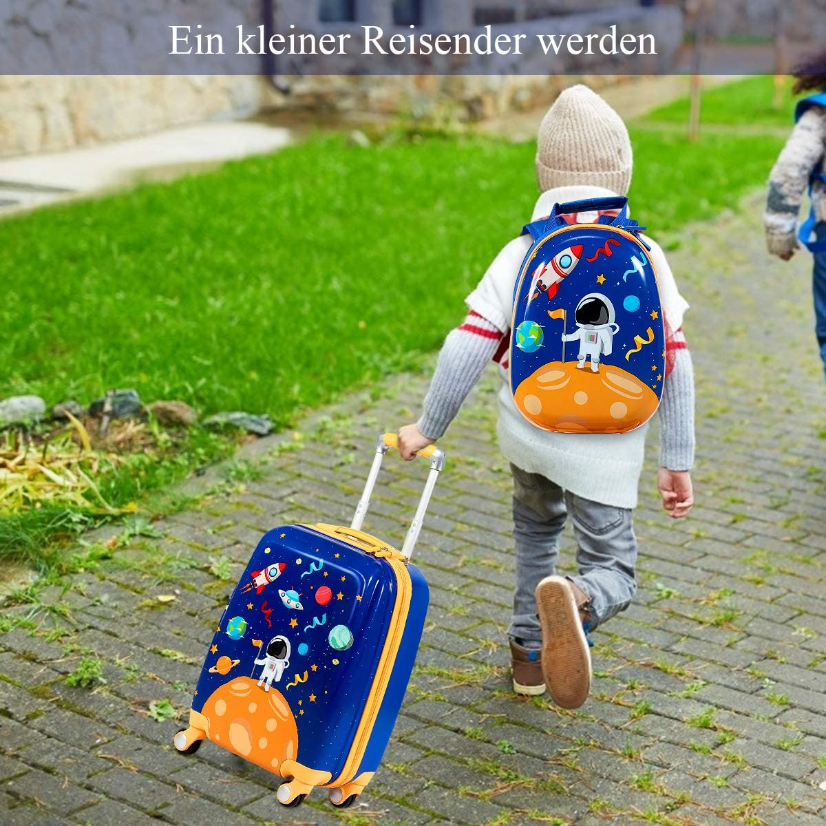 Ein Kind zieht einen blauen Koffer mit Astronautenmotiv, geht auf einem Gehweg.