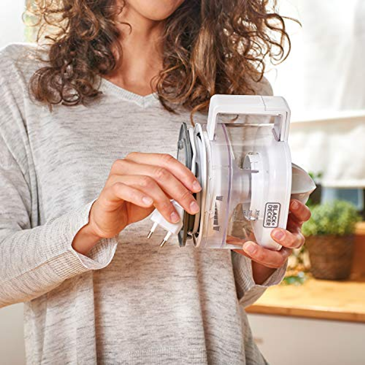 A woman holding a white and clear vacuum cleaner.