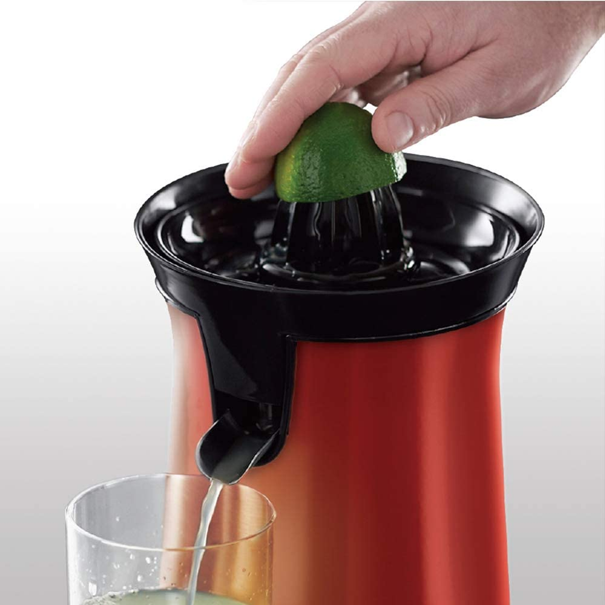 Hand presst eine Limette in eine Saftpresse, Saft fließt.