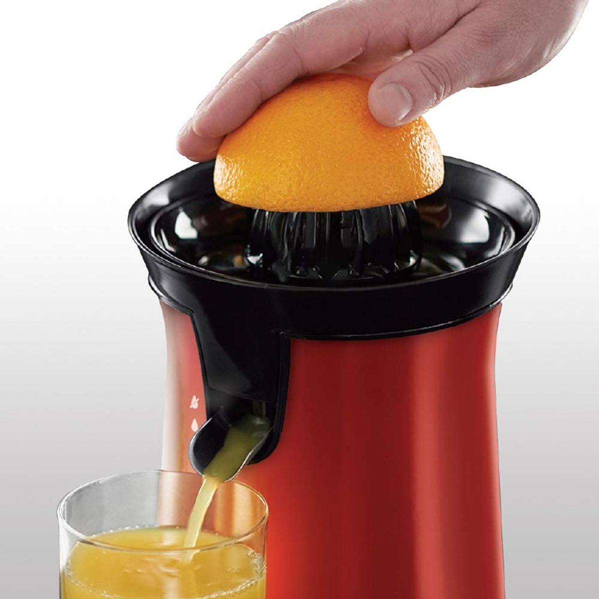Roter und schwarzer Entsafter, Orangen werden in ein Glas gepresst.