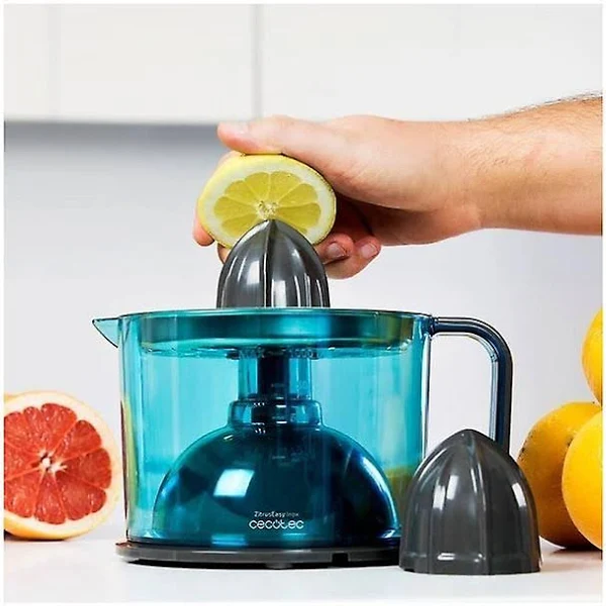 Persona exprimiendo limón con exprimidor. Contenedor azul con limones.