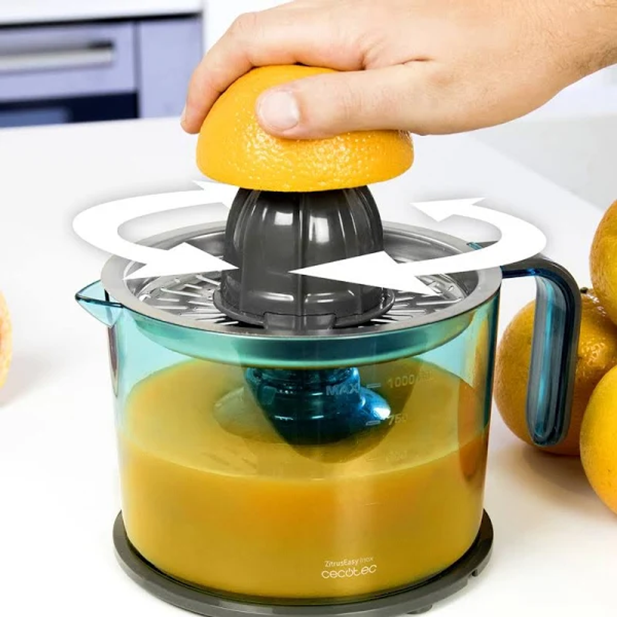 Una mano exprimiendo una naranja en un exprimidor, jugo en el recipiente.