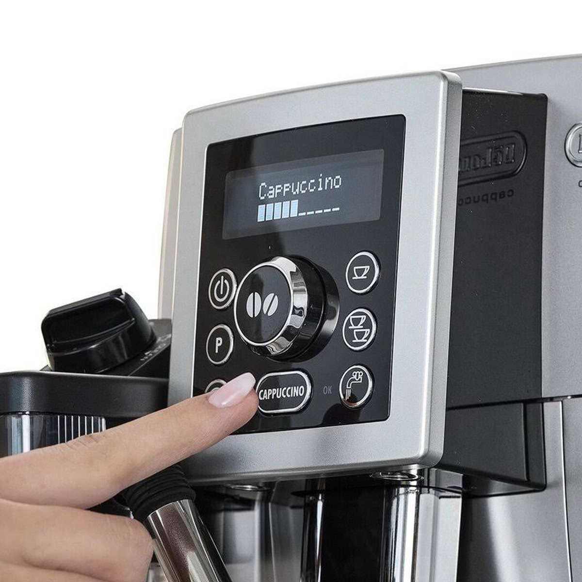 Panel de control de la cafetera que muestra 'Cappuccino' y barra de progreso. Una mano presiona el botón de cappuccino.