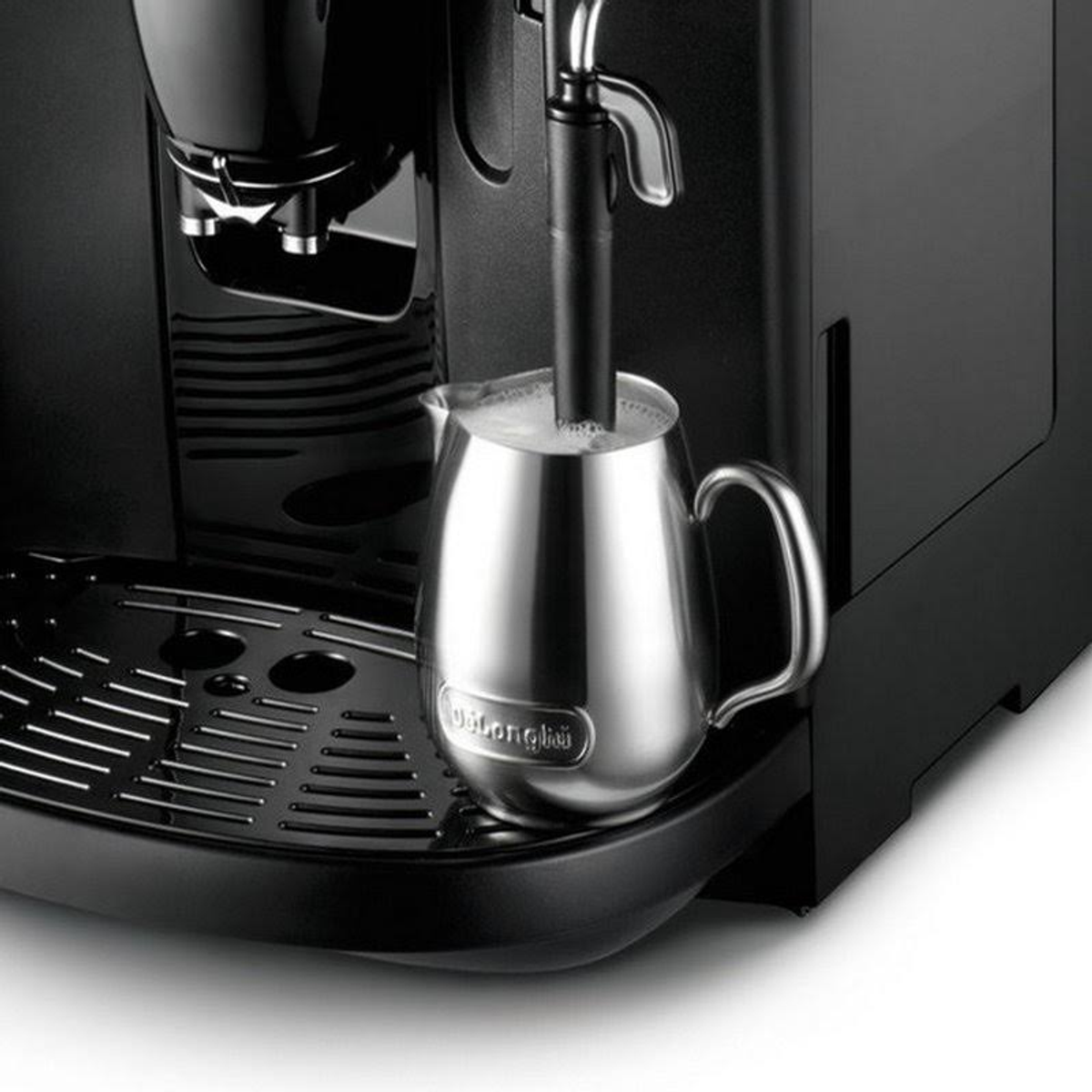 Primer plano de una cafetera con una jarra espumadora de leche de acero inoxidable, la máquina y la jarra son negras.