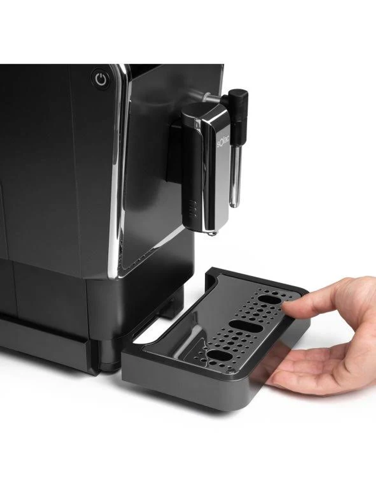 Ręka wyjmująca tackę ociekową z czarnego ekspresu do kawy.