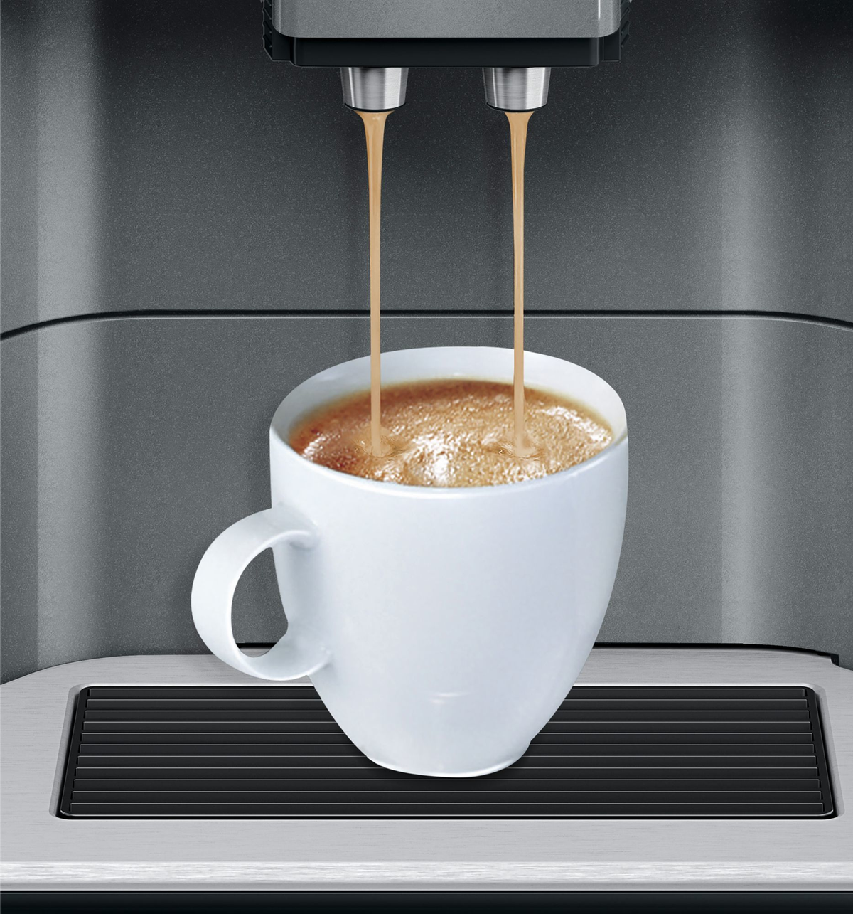 Macchina del caffè che versa il caffè in una tazza bianca. La macchina è grigia, lo sfondo è grigio.