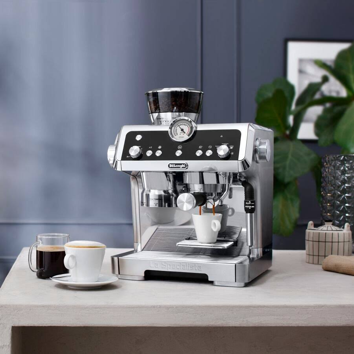 Espresso döken beyaz bir fincan ve bir fincan kahve ile gümüş bir espresso makinesi.