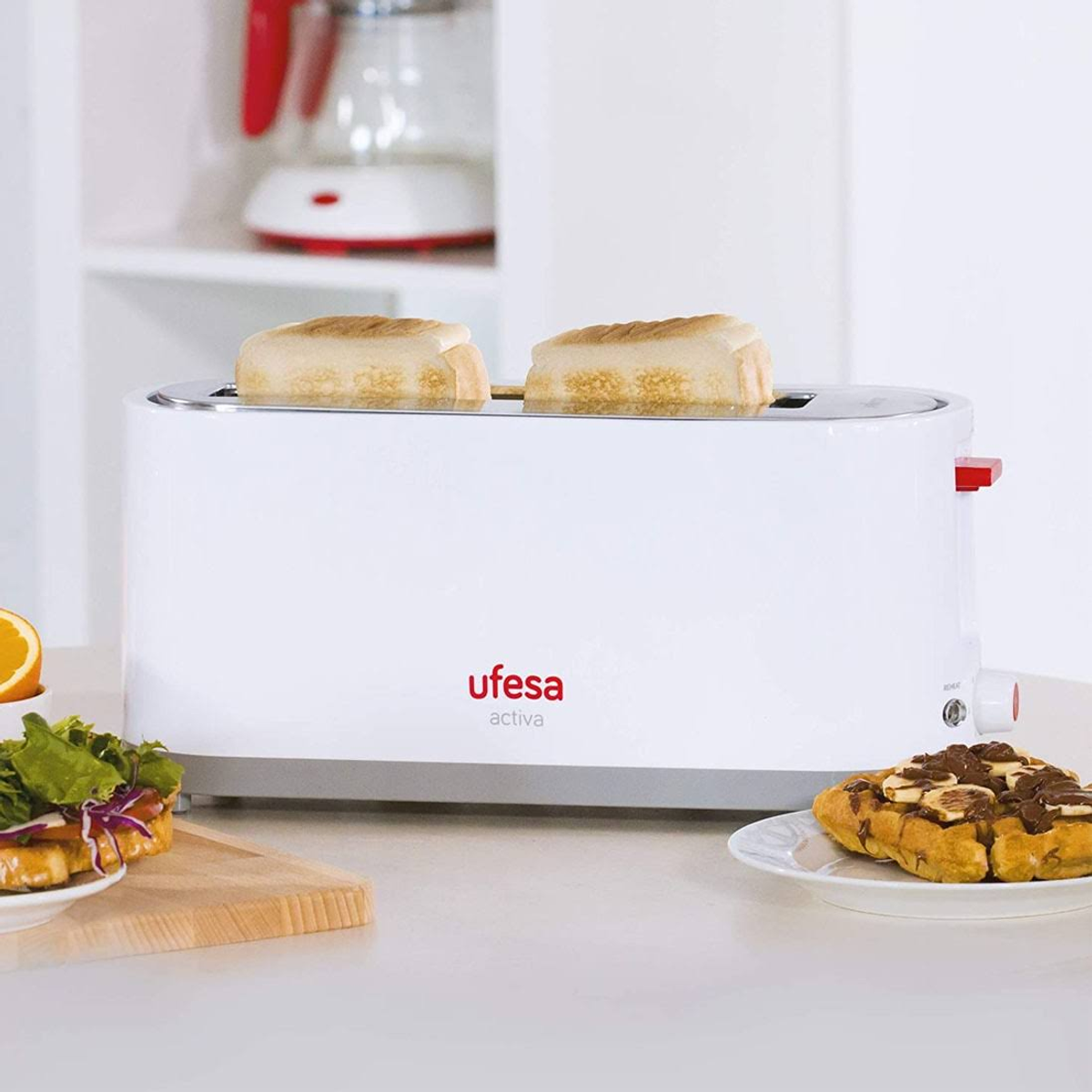 Biały toster z dwoma kromkami chleba. Obok talerz z goframi i sałatką.