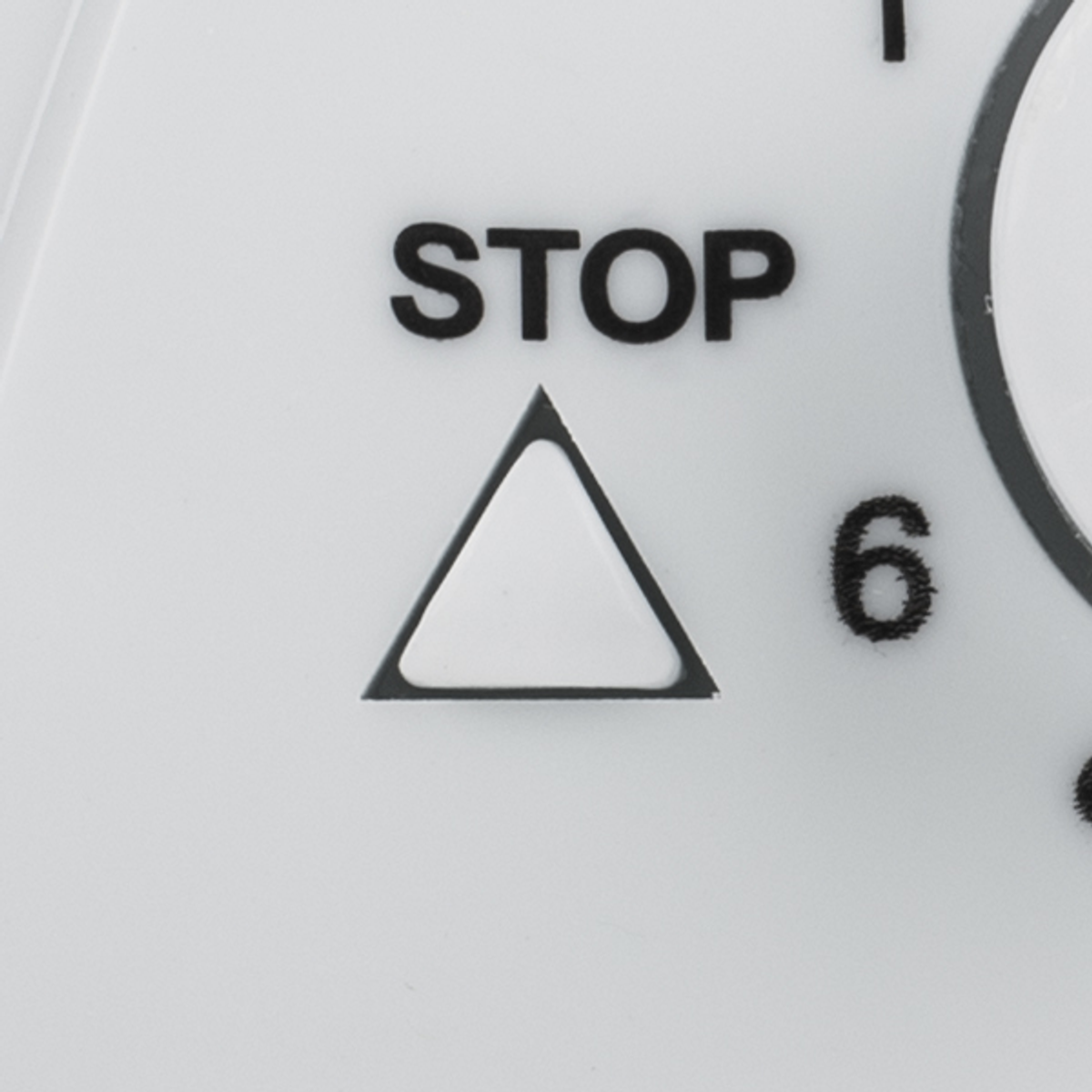 Zbliżenie białego przycisku ze słowem STOP i symbolem trójkąta.