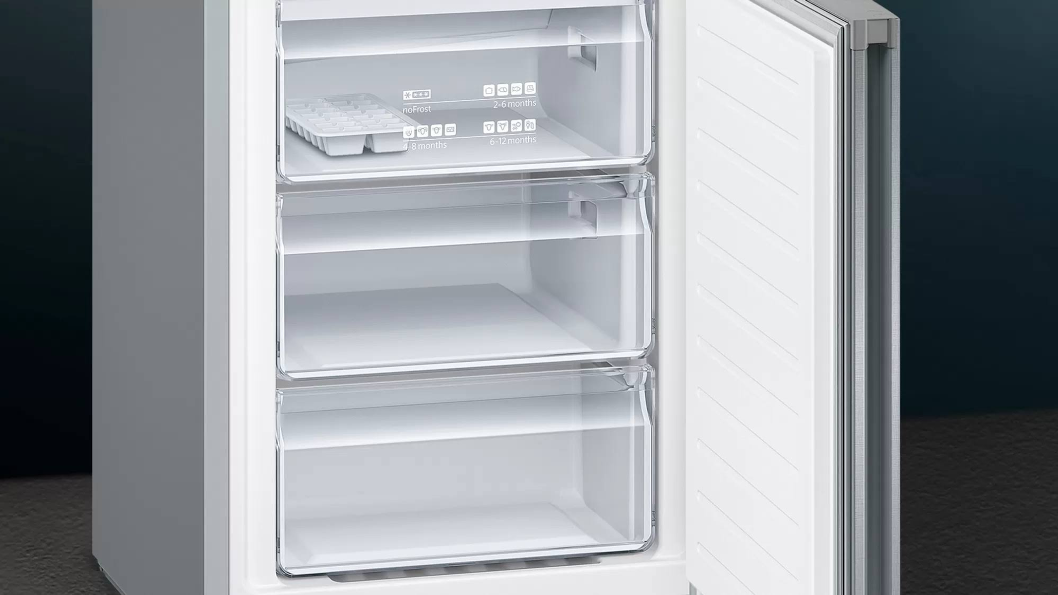 Refrigerador abierto con tres cajones transparentes, mostrando el interior con elementos.