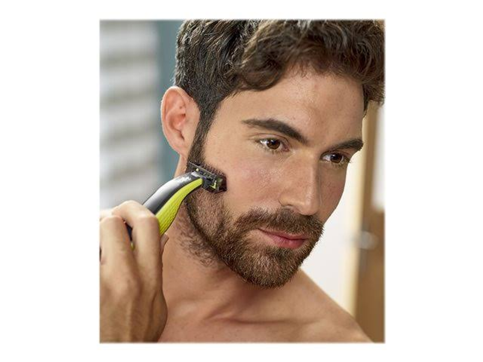 Un uomo si rade la barba con un rasoio elettrico verde e giallo.