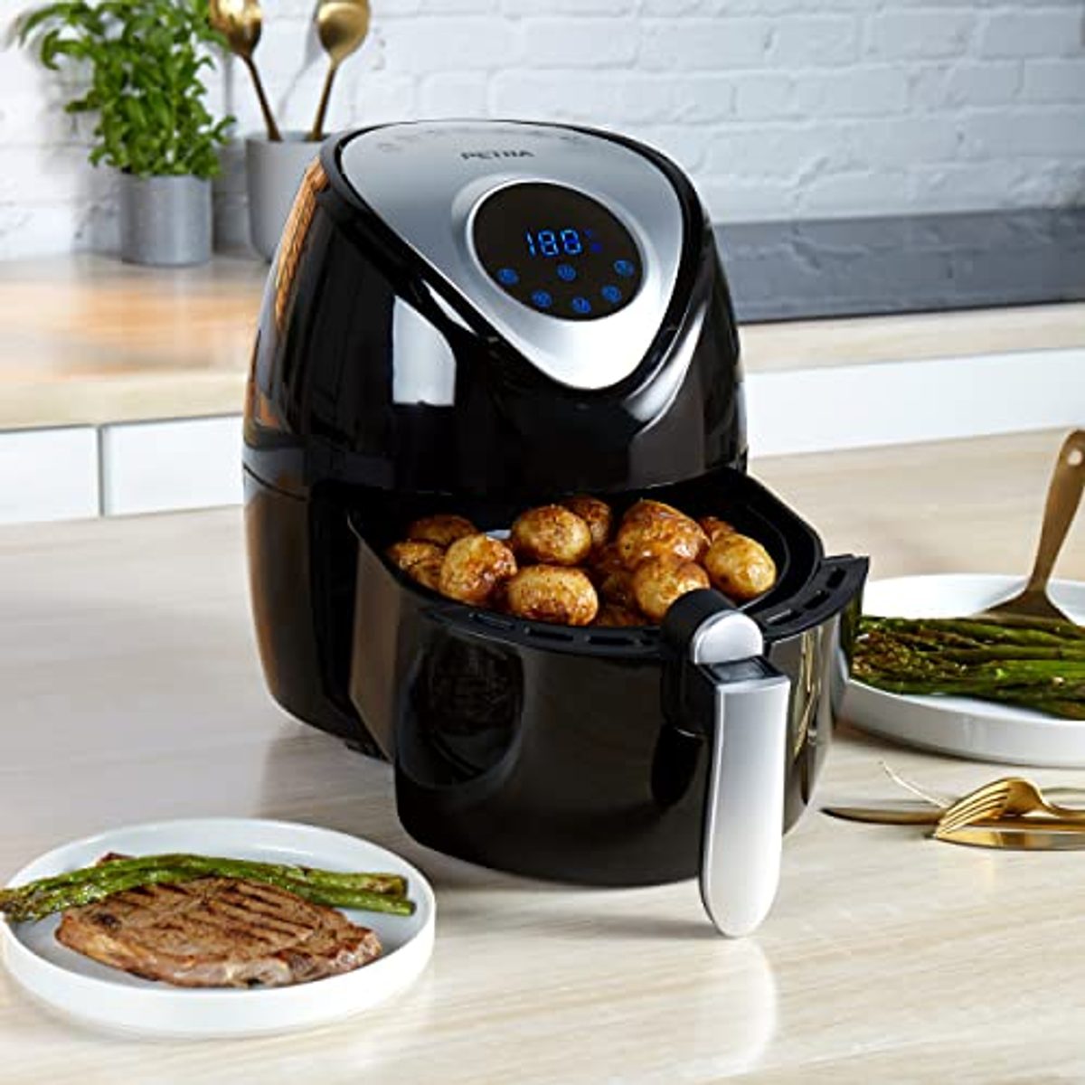 Friggitrice ad aria nera con cibo dentro, cibo grigliato e asparagi.