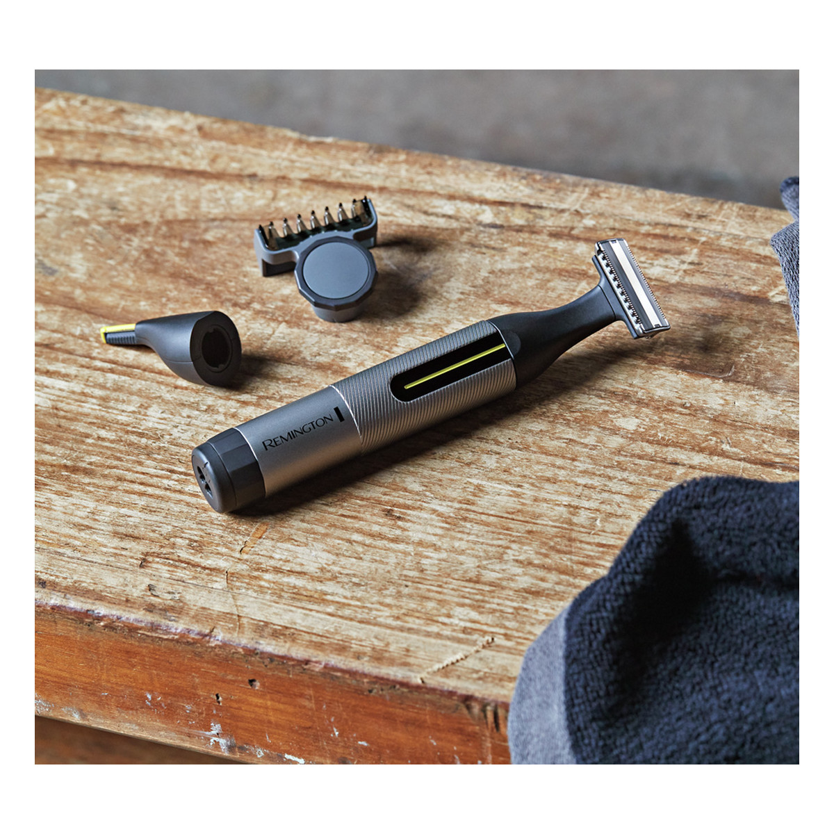 Rasoio elettrico con accessori su una superficie di legno. È di colore grigio e nero.