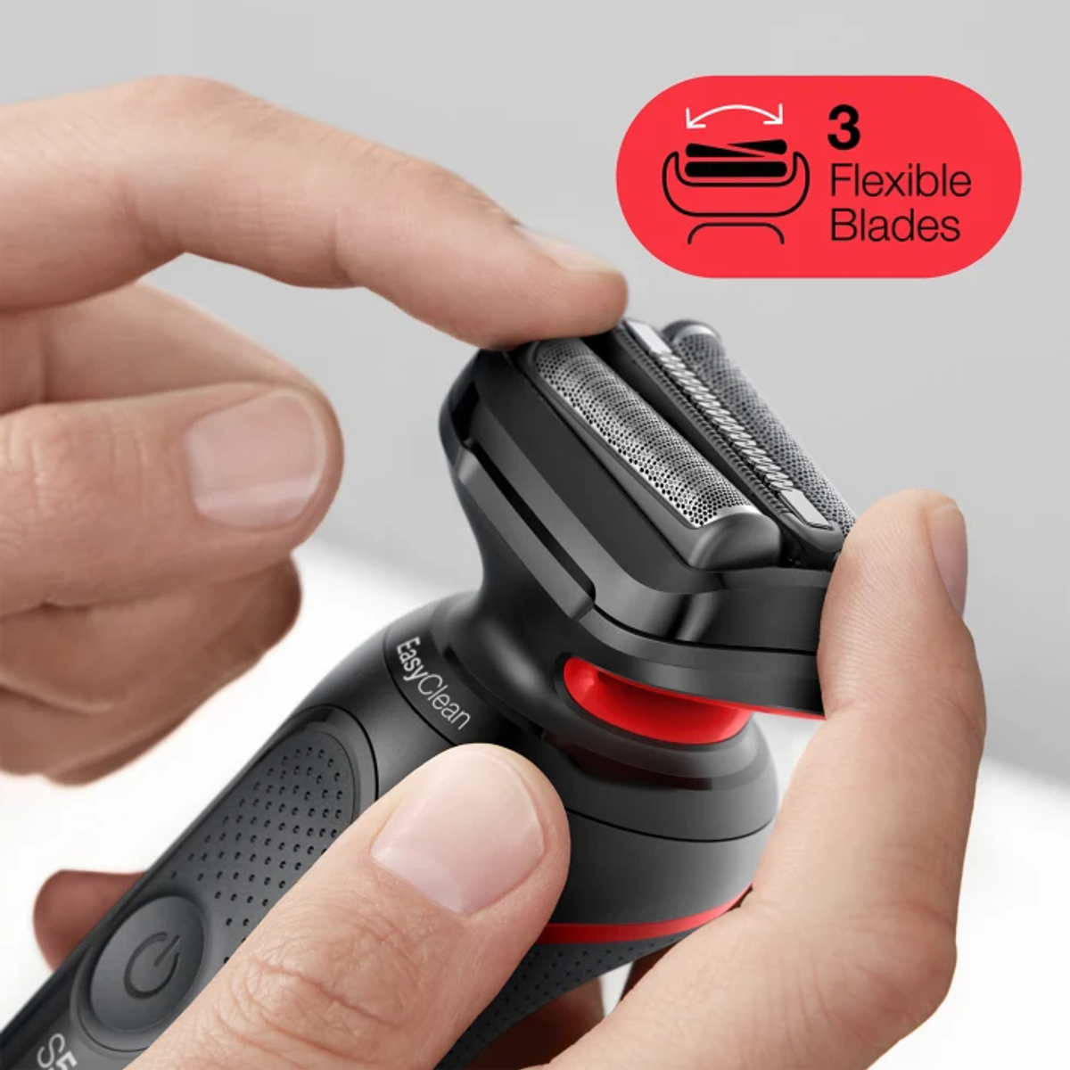 Dłoń dotyka 3 elastycznych ostrzy czarnej golarki elektrycznej.