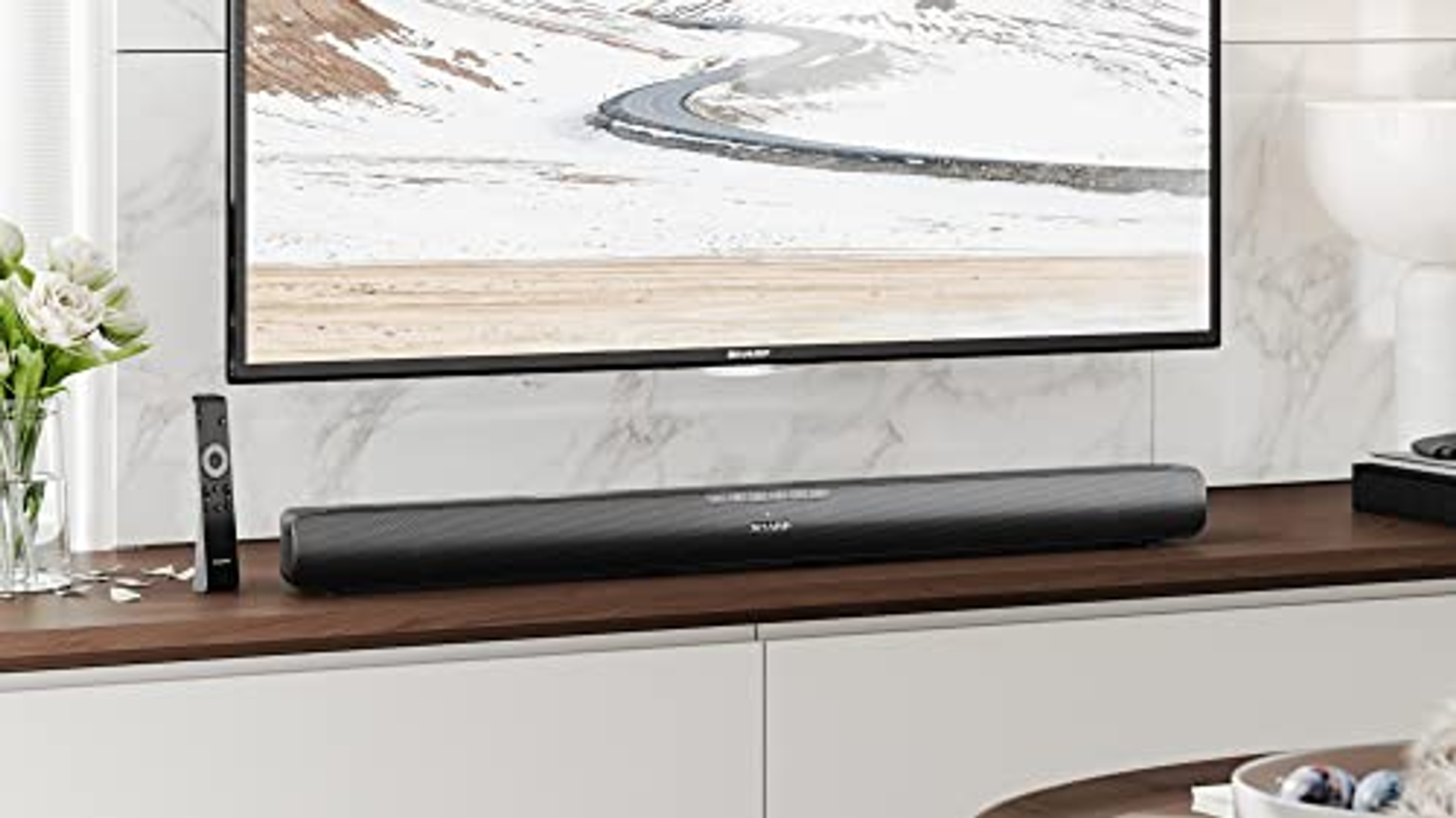 Black soundbar on a white cabinet. TV and remote are also visible.